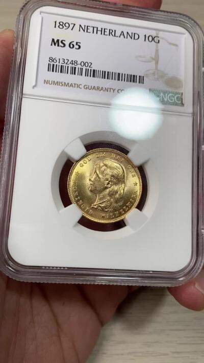 万国钱币拍卖第055期 NGC MS65 1897年荷兰威廉明娜女王萝莉头10盾金币 发行量不到50万枚 顶级镜面BU光泽丝绸底板收藏级 6.45G 900金