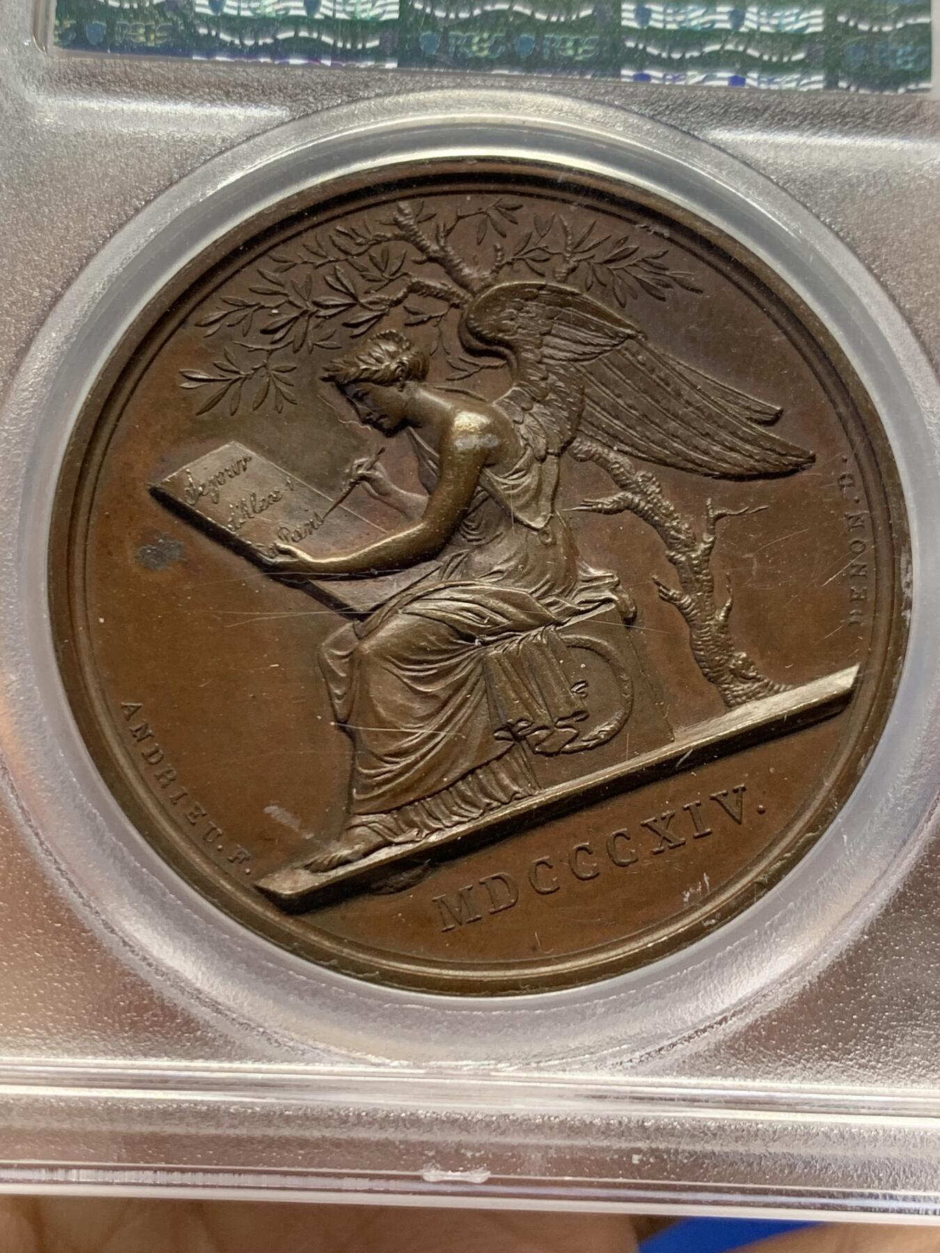 《竞宝斋》第438场 周日，周一，周二 3场连拍 （全场包邮） PCGS SP64 亚军分 法国1814年沙皇亚历山大一世访问巴黎铜章 正面沙皇月桂冠高浮雕，完全拿章典型风格头像，背面天使坐于树荫下书写历史，纪念沙皇占领期访巴黎造币厂，第六次反法同盟胜利，法兰西第一帝国覆灭，拿皇退位流放，巴黎由俄军掌管。作为胜利者的沙皇骑着白马率大军通过凯旋门，不知他是否满脑一年前拿皇攻占莫斯科场景，与其说“访问巴黎”，不如说彰显复仇拿皇的耀武扬威。