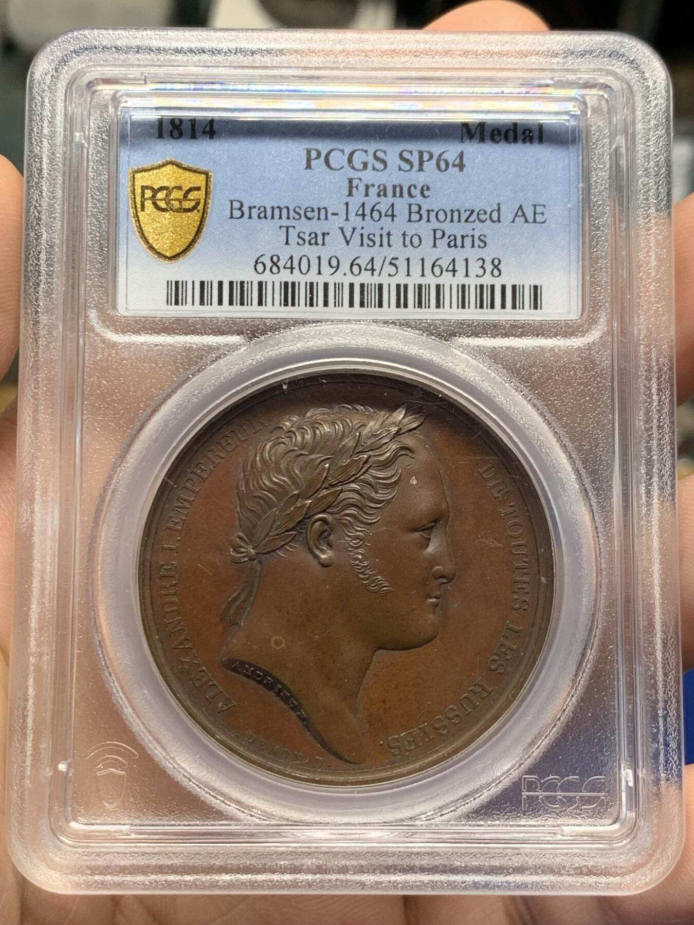 《竞宝斋》第438场 周日，周一，周二 3场连拍 （全场包邮） PCGS SP64 亚军分 法国1814年沙皇亚历山大一世访问巴黎铜章 正面沙皇月桂冠高浮雕，完全拿章典型风格头像，背面天使坐于树荫下书写历史，纪念沙皇占领期访巴黎造币厂，第六次反法同盟胜利，法兰西第一帝国覆灭，拿皇退位流放，巴黎由俄军掌管。作为胜利者的沙皇骑着白马率大军通过凯旋门，不知他是否满脑一年前拿皇攻占莫斯科场景，与其说“访问巴黎”，不如说彰显复仇拿皇的耀武扬威。