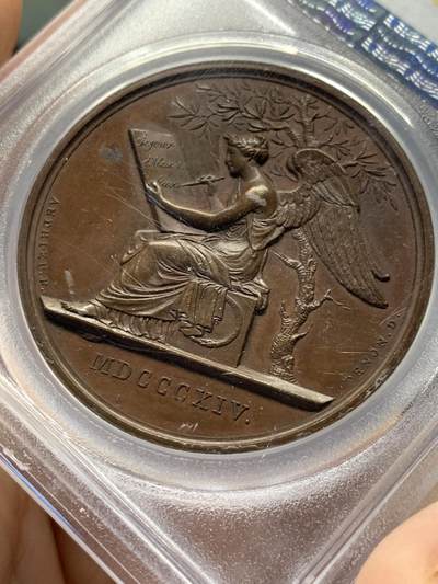 《竞宝斋》第438场 周日，周一，周二 3场连拍 （全场包邮） PCGS SP64 亚军分 法国1814年沙皇亚历山大一世访问巴黎铜章 正面沙皇月桂冠高浮雕，完全拿章典型风格头像，背面天使坐于树荫下书写历史，纪念沙皇占领期访巴黎造币厂，第六次反法同盟胜利，法兰西第一帝国覆灭，拿皇退位流放，巴黎由俄军掌管。作为胜利者的沙皇骑着白马率大军通过凯旋门，不知他是否满脑一年前拿皇攻占莫斯科场景，与其说“访问巴黎”，不如说彰显复仇拿皇的耀武扬威。