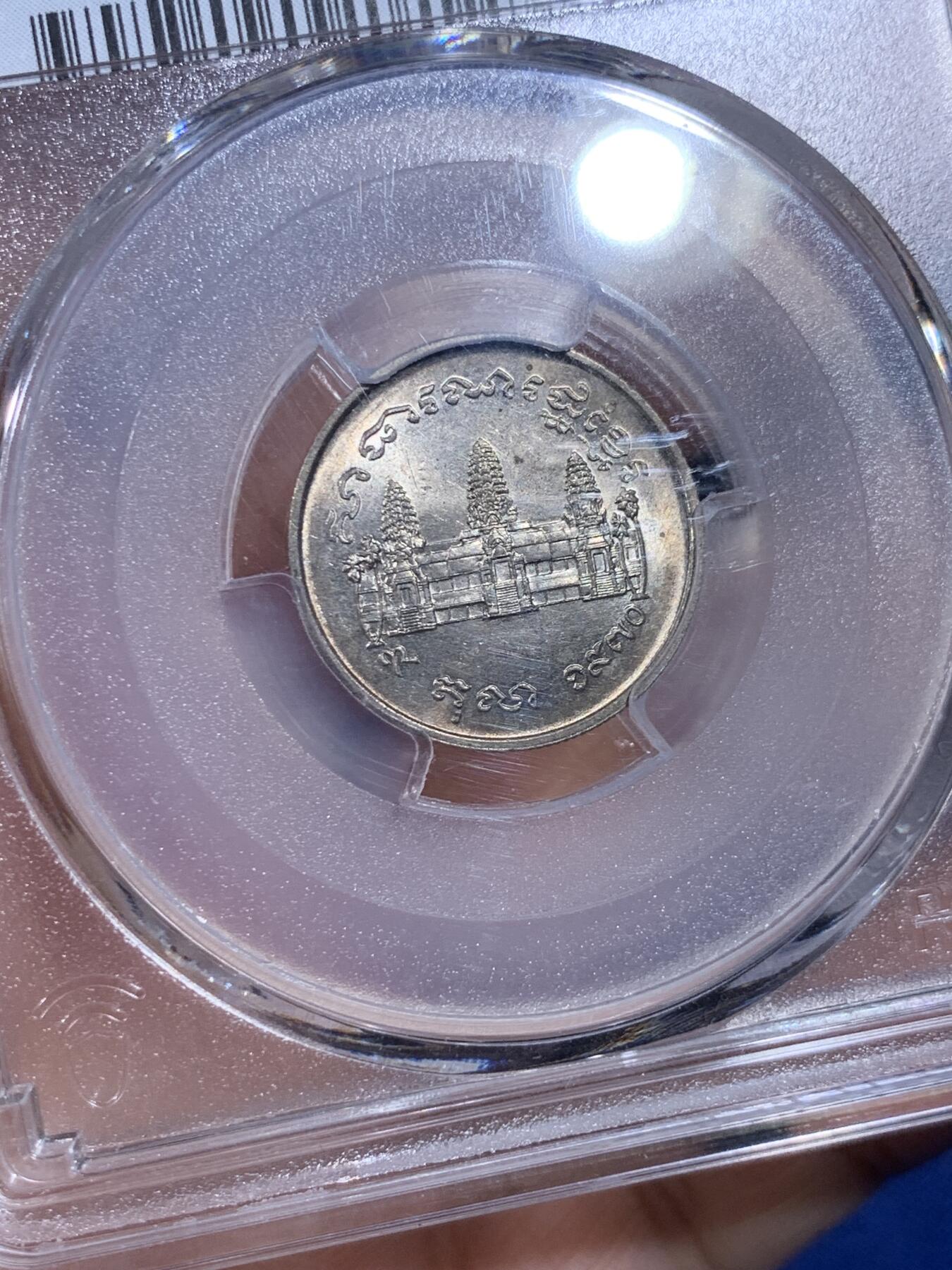 《竞宝斋》第439场 周日，周一，周二 3场连拍 （全场包邮） PCGS MS65 柬埔寨红色高棉政权发行的纪念币。英国皇家造币厂代工。1971年并没有发行。直到1980年代后市面上才陆续见到。数量稀少，盒子左上角有内裂纹。