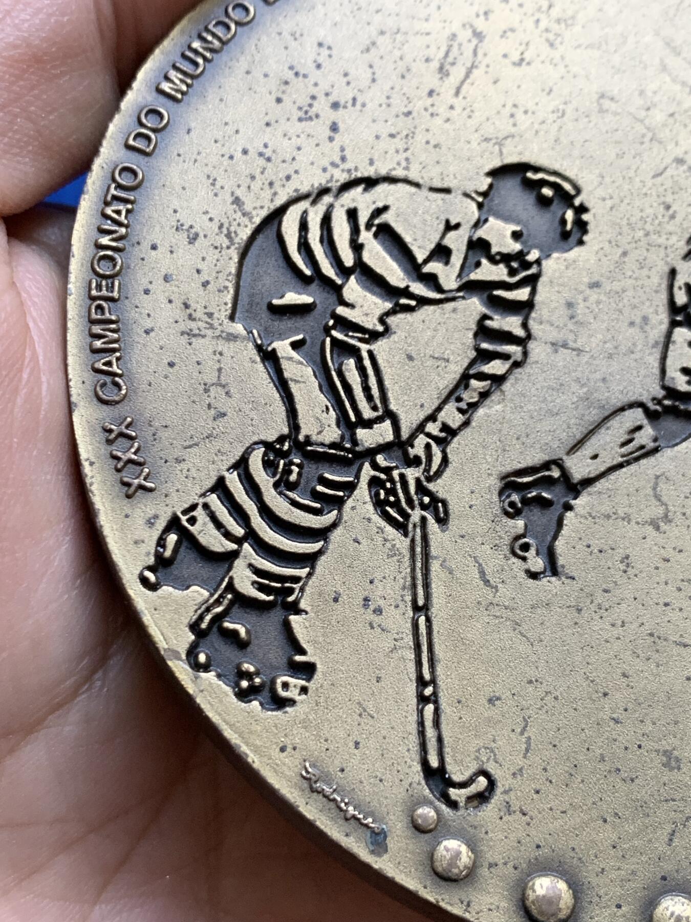 《竞宝斋》第439场 周日，周一，周二 3场连拍 （全场包邮） 葡萄牙1991年第30届曲棍球世界锦标赛异形铜章，长9.7cm，重480克。非常有趣的设计。不采用浮雕，正反面人物和城市景观都采用低于章面的凹版雕刻手法。