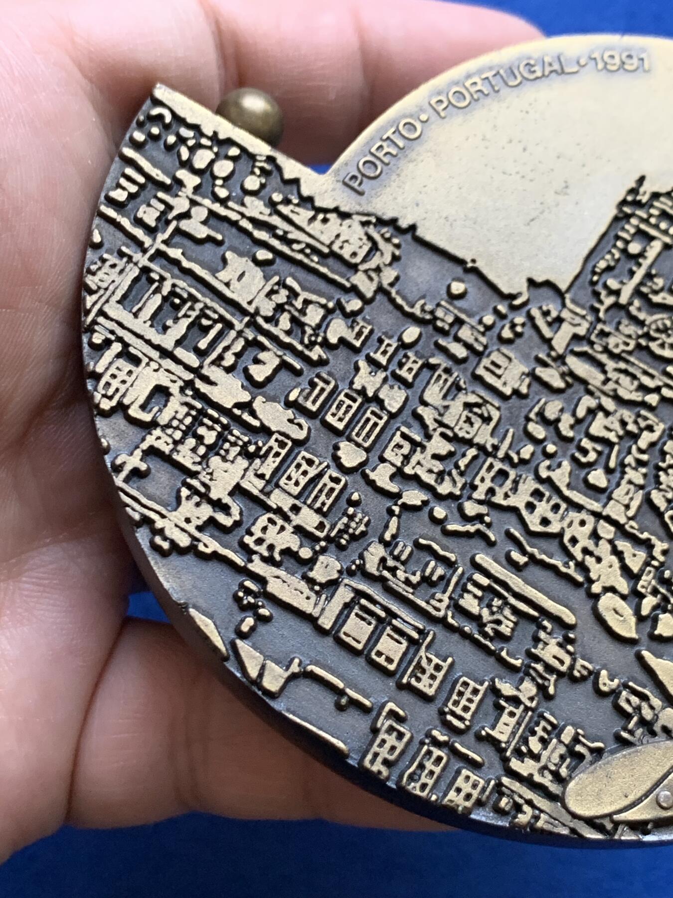 《竞宝斋》第439场 周日，周一，周二 3场连拍 （全场包邮） 葡萄牙1991年第30届曲棍球世界锦标赛异形铜章，长9.7cm，重480克。非常有趣的设计。不采用浮雕，正反面人物和城市景观都采用低于章面的凹版雕刻手法。