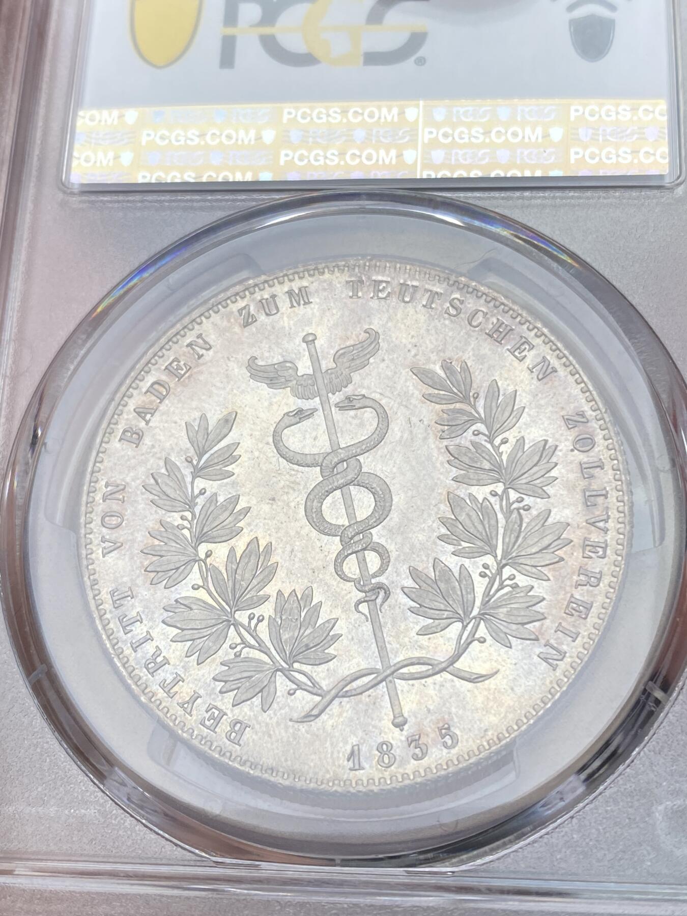 万国钱币拍卖第055期 PCGS MS64 1835年巴伐利亚路德维希一世纪念巴登加入关税同盟历史大泰勒 热门历史系列 无论工艺还是设计都是同时代中的佼佼者 双蛇缠绕的权杖是商业之神赫尔墨斯的象征 底板类镜面喷砂质感 64已是极其难得 越来越贵的品种