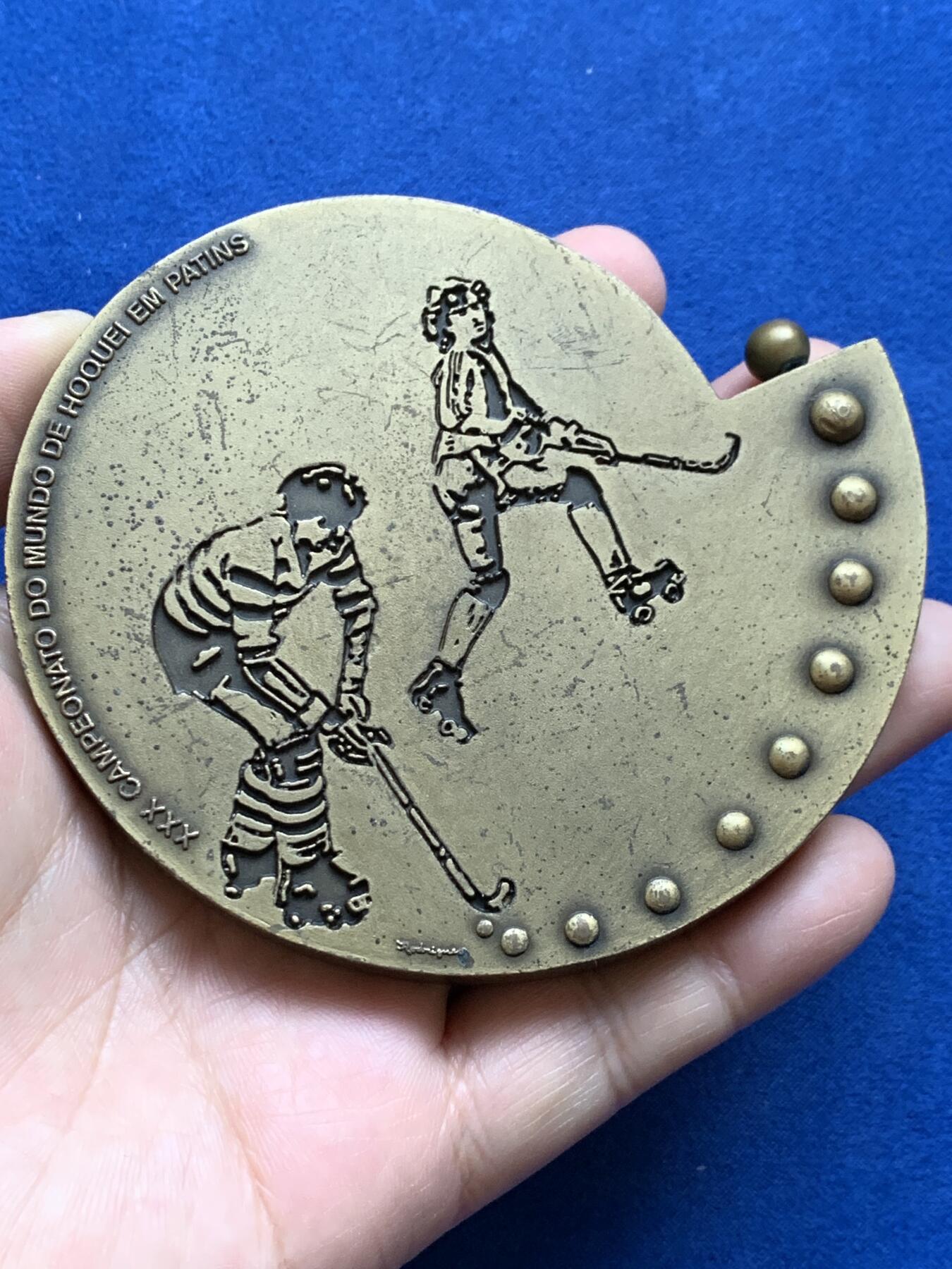 《竞宝斋》第439场 周日，周一，周二 3场连拍 （全场包邮） 葡萄牙1991年第30届曲棍球世界锦标赛异形铜章，长9.7cm，重480克。非常有趣的设计。不采用浮雕，正反面人物和城市景观都采用低于章面的凹版雕刻手法。