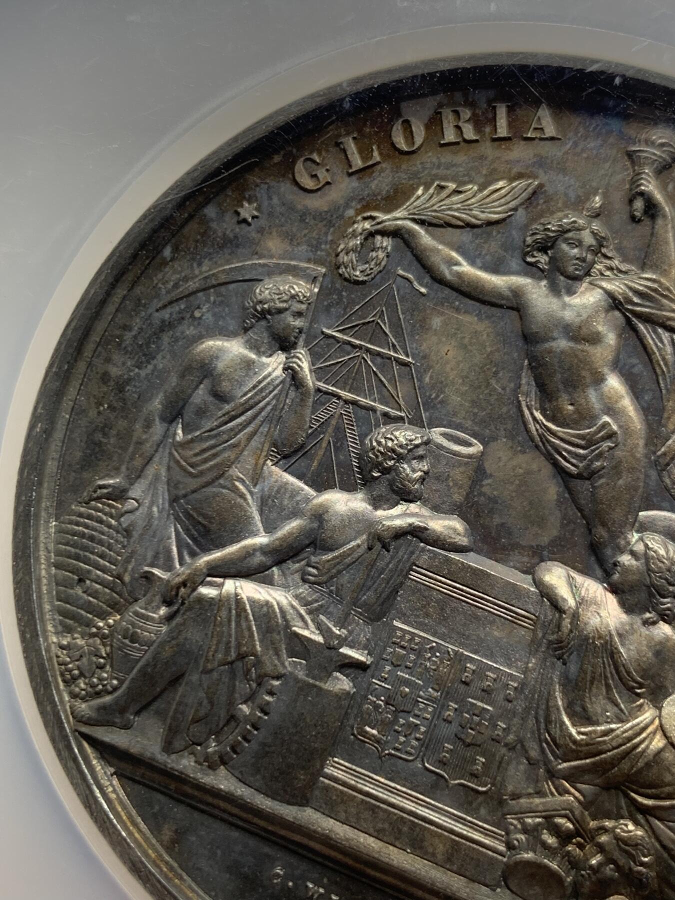 《竞宝斋》第440场 周日，周一，周二 3场连拍 （全场包邮） NGC MS61 葡萄牙1865年波尔多国际博览会大银章，首见品，高浮雕，深彩包浆，艺术性强，正面5个神话人物雕刻细腻，无磨损。赏心悦目爱不释手，这样的大银章很少见了。艺术价值高，值得珍藏。加大加厚盒。著名雕刻家：C.Wiener作品。直径：58mm，重：76g。