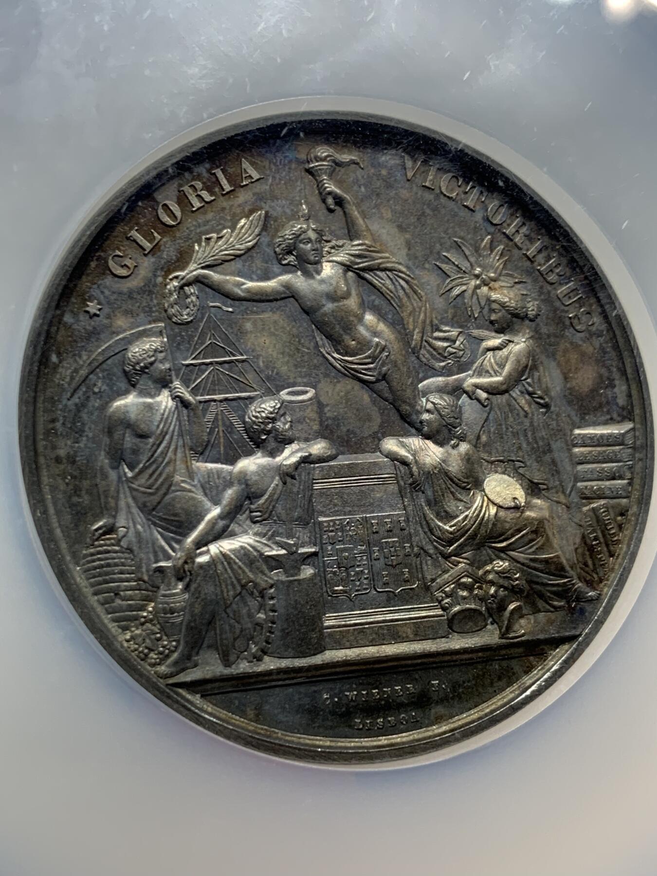 《竞宝斋》第440场 周日，周一，周二 3场连拍 （全场包邮） NGC MS61 葡萄牙1865年波尔多国际博览会大银章，首见品，高浮雕，深彩包浆，艺术性强，正面5个神话人物雕刻细腻，无磨损。赏心悦目爱不释手，这样的大银章很少见了。艺术价值高，值得珍藏。加大加厚盒。著名雕刻家：C.Wiener作品。直径：58mm，重：76g。