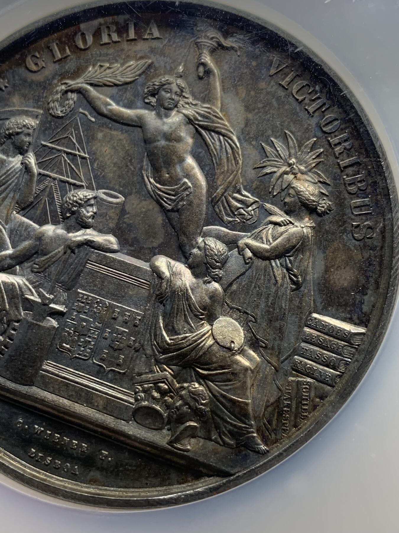 《竞宝斋》第440场 周日，周一，周二 3场连拍 （全场包邮） NGC MS61 葡萄牙1865年波尔多国际博览会大银章，首见品，高浮雕，深彩包浆，艺术性强，正面5个神话人物雕刻细腻，无磨损。赏心悦目爱不释手，这样的大银章很少见了。艺术价值高，值得珍藏。加大加厚盒。著名雕刻家：C.Wiener作品。直径：58mm，重：76g。