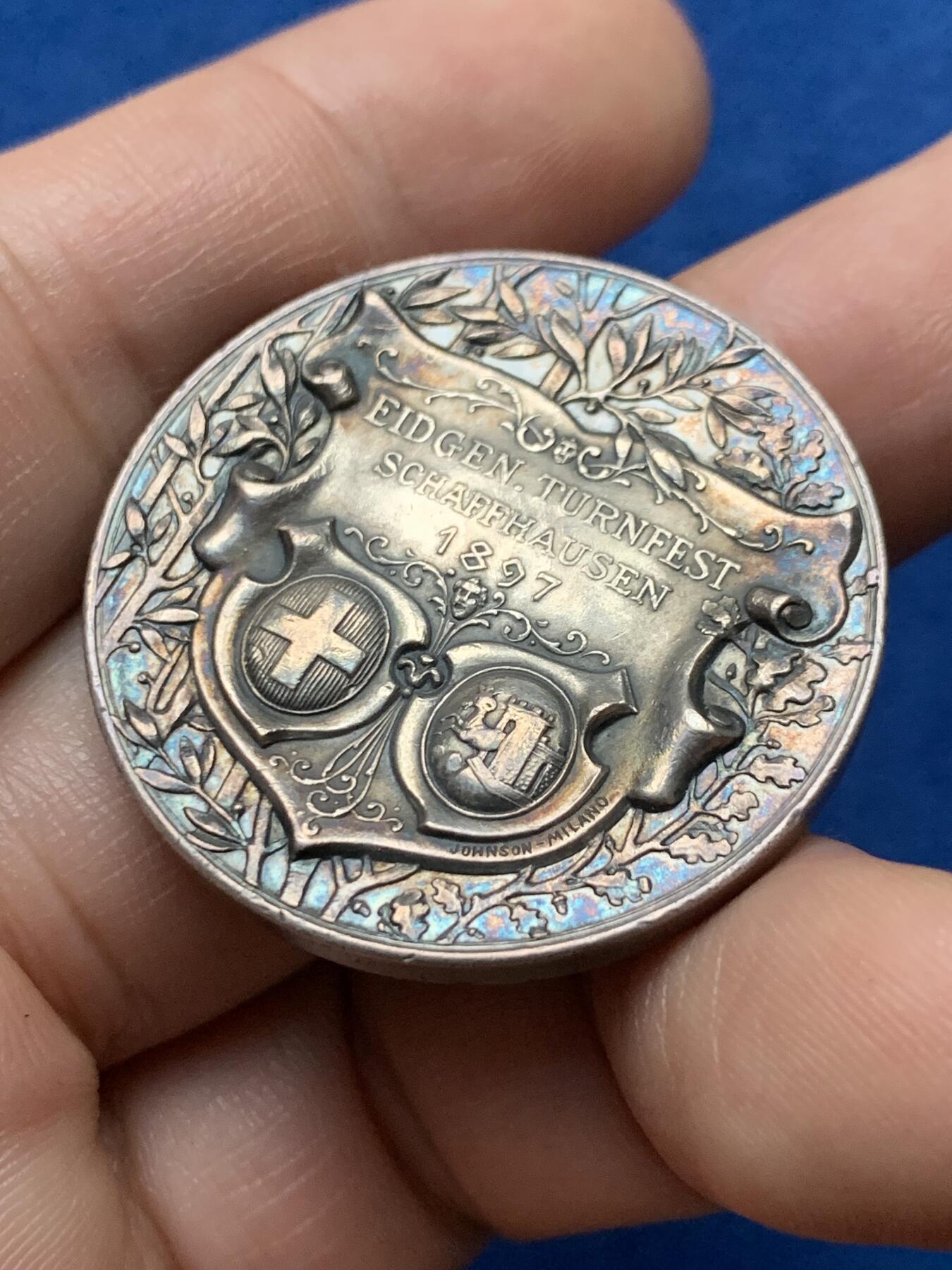 《竞宝斋》第440场 周日，周一，周二 3场连拍 （全场包邮） 1897年瑞士沙夫豪森体操节银章，19.6g，35mm，双面彩色包浆，正面凹面高浮雕设计，背景是瑞士特有的高原山地城池风景，背面橄榄和橡树枝之上的是沙夫豪森和瑞士盾徽