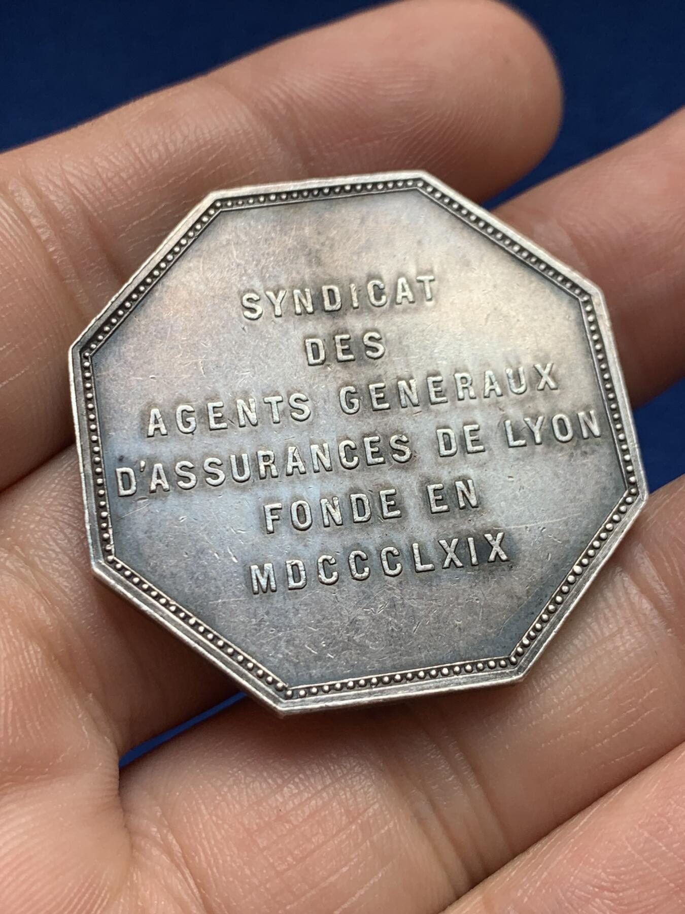 《竞宝斋》第440场 周日，周一，周二 3场连拍 （全场包邮） 1869年里昂综合保险银质八角代币，稀少品种，正面雄狮手持大宝剑图案，直径：36mm，重：21.6g