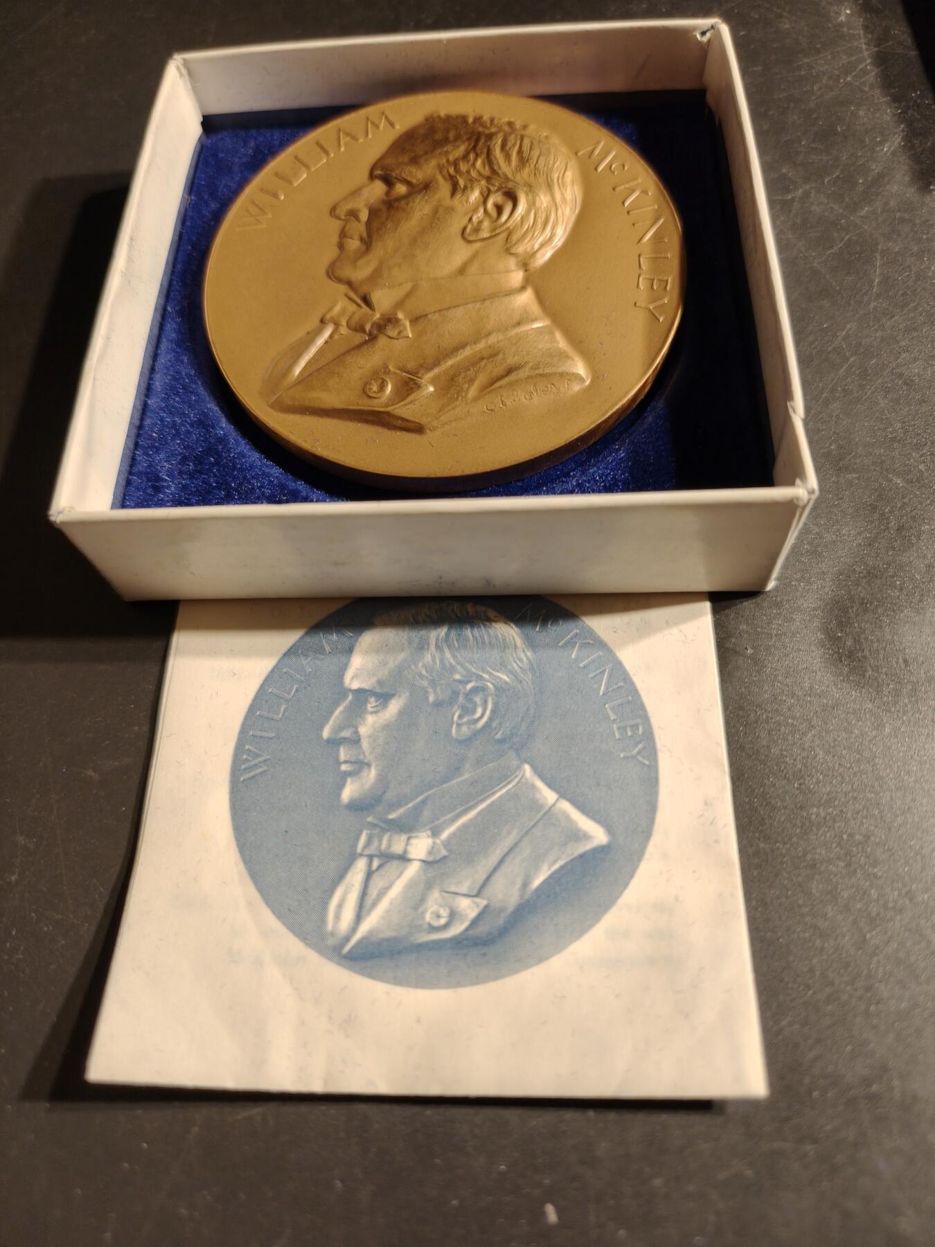 老王徽章第164期 美国铸币局威廉•麦金利总统大铜章     原盒带证书     直径76mm.   重量227.2g.    威廉·麦金利是美国第25任总统，任期从1897年3月4日开始，直至1901年9月14日遇刺身亡。他是最后一位曾参加南北战争的美国总统。  纪念章通常用于纪念特定人物或事件，其价值取决于稀有性、历史背景和保存状况。背面描绘了一个女性形象，可能象征着哀悼或自由   