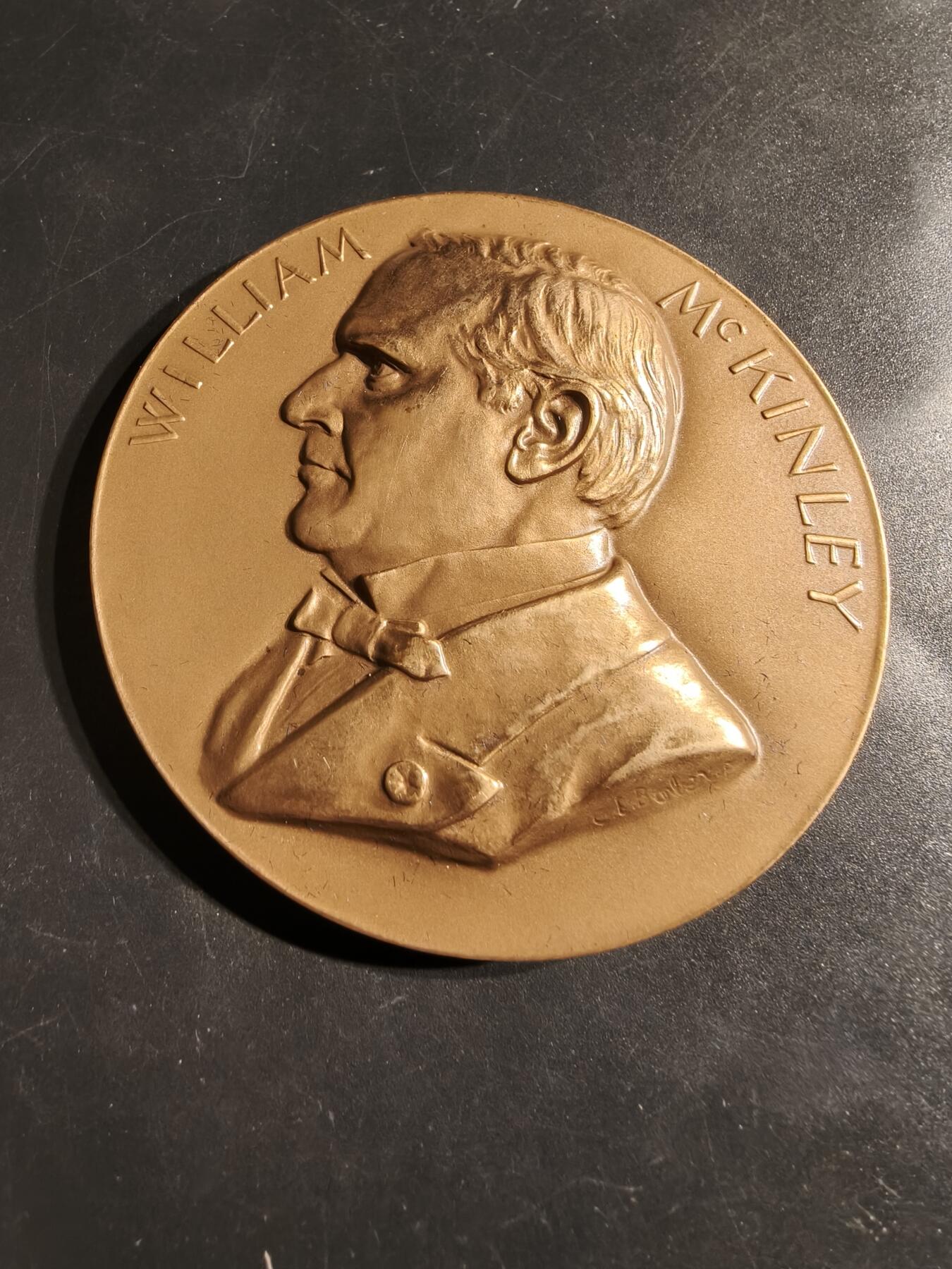 老王徽章第164期 美国铸币局威廉•麦金利总统大铜章     原盒带证书     直径76mm.   重量227.2g.    威廉·麦金利是美国第25任总统，任期从1897年3月4日开始，直至1901年9月14日遇刺身亡。他是最后一位曾参加南北战争的美国总统。  纪念章通常用于纪念特定人物或事件，其价值取决于稀有性、历史背景和保存状况。背面描绘了一个女性形象，可能象征着哀悼或自由   