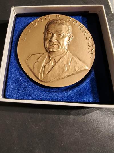 老王徽章第164期 -  美国铸币局林登约翰逊总统大铜章     原盒     直径76mm.    重量216g.     铜章上的文字引用了约翰逊总统就职演说的一部分：“在此之际，我在您和上帝面前所宣读的誓言，不仅是我个人的，更是我们共同的。我们是一个国家，一个民族……”。