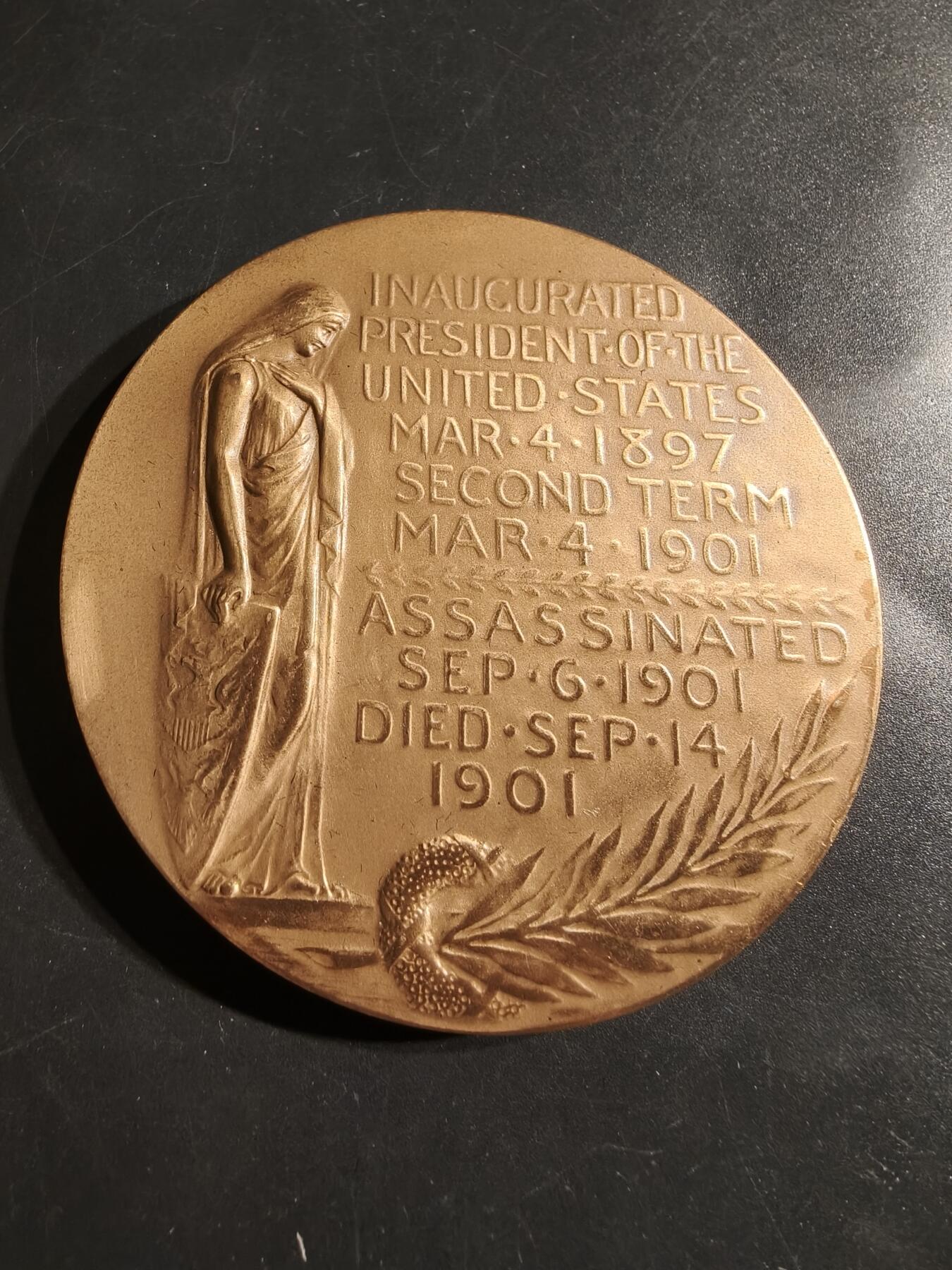 老王徽章第164期 美国铸币局威廉•麦金利总统大铜章     原盒带证书     直径76mm.   重量227.2g.    威廉·麦金利是美国第25任总统，任期从1897年3月4日开始，直至1901年9月14日遇刺身亡。他是最后一位曾参加南北战争的美国总统。  纪念章通常用于纪念特定人物或事件，其价值取决于稀有性、历史背景和保存状况。背面描绘了一个女性形象，可能象征着哀悼或自由   
