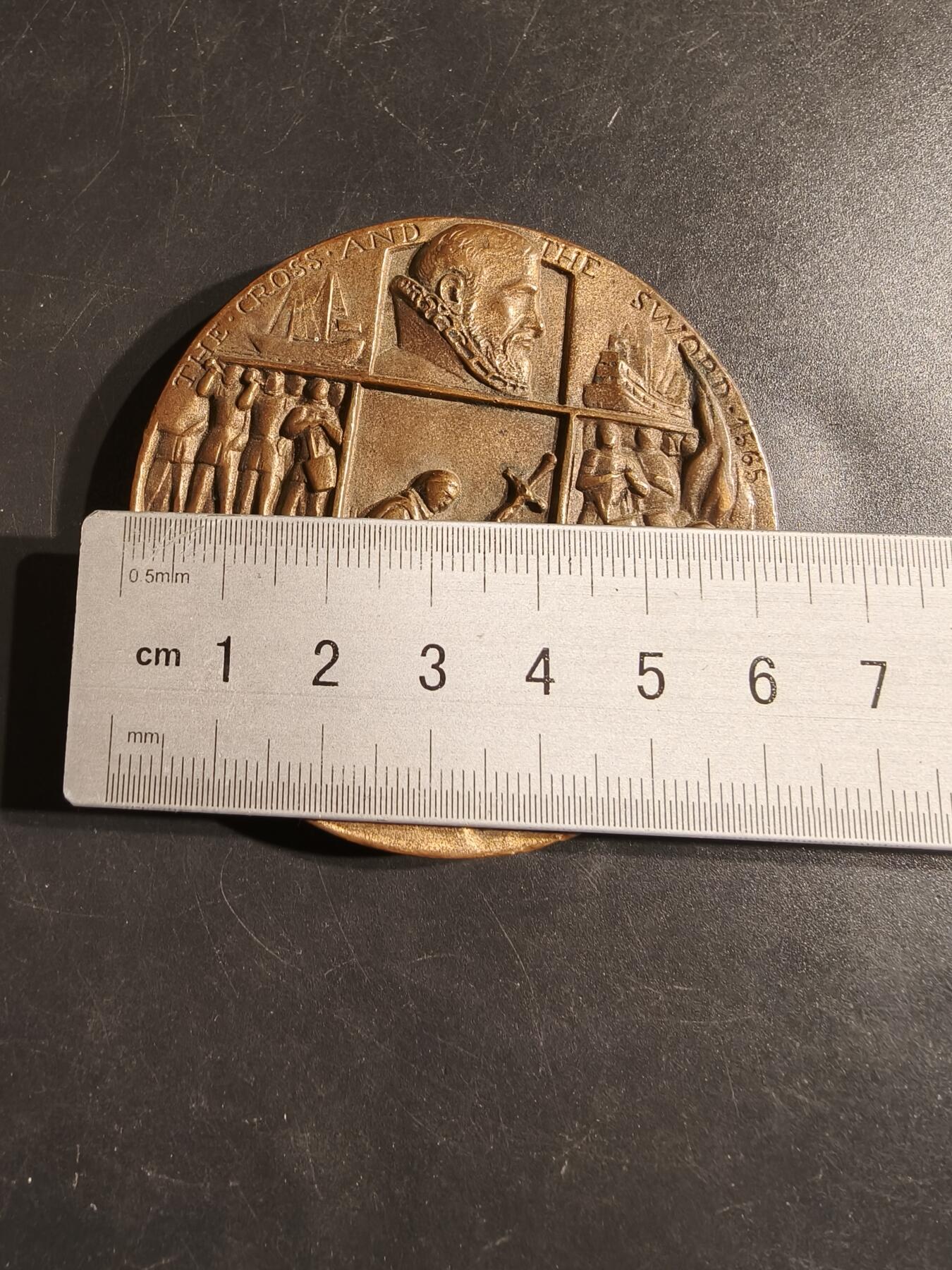 老王徽章第164期 美国佛罗里达州圣奥古斯丁市400周年大铜章      高浮雕     直径62mm.    重量182.4g.    该铜章刻有“THE CROSS AND THE SWORD - 1565”（十字架与剑- 1565）字样，描绘了传教士和士兵到达的场景。