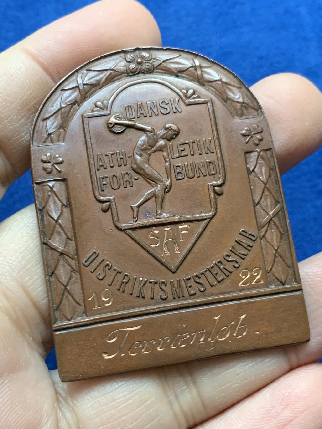 《竞宝斋》第442场 周日，周一，2场连拍 （全场包邮） 丹麦王国1922年国家田径越野竞赛异形铜章，实名刻发，背带厂标， 尺寸54.8m m×41.7mm，重量40.95g，百年巧克力包浆美品。