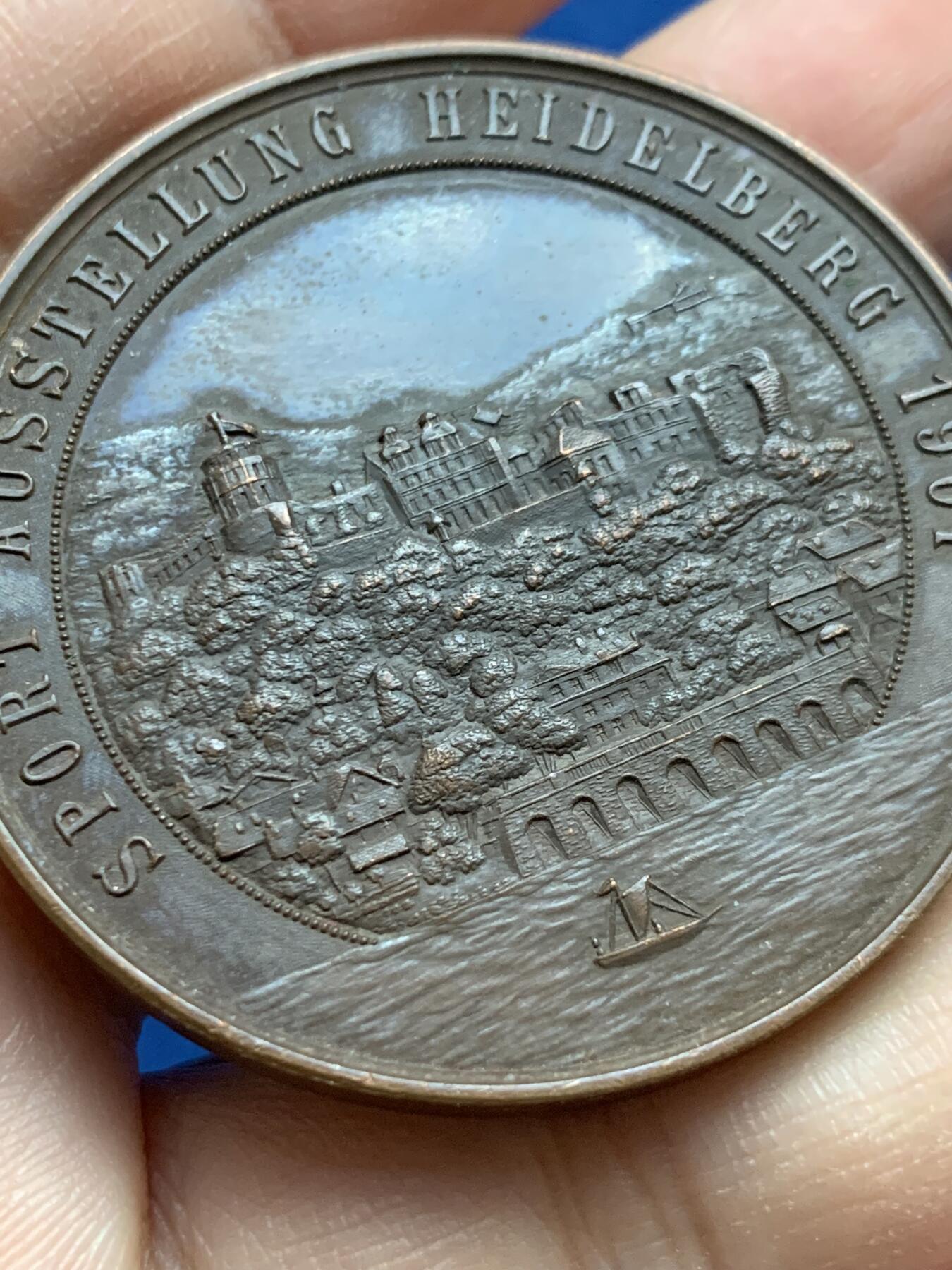 《竞宝斋》第442场 周日，周一，2场连拍 （全场包邮） 德国第二帝国1901年景观奖章-体育奥斯塔隆海德堡，材质青铜，直径45MM，重40.5g 。这枚奖章是在1901在德意志帝国(第二帝国)为了纪念ausstellung(体育展览)持有时间海德堡。当时，德国正经历着快速的工业化，人们对有组织的体育、体育和公共展览的兴趣日益浓厚。这项活动可能展示了田径、体操和其他体育学科的进步，反映了威廉明时代国家对健康和健身的重视。