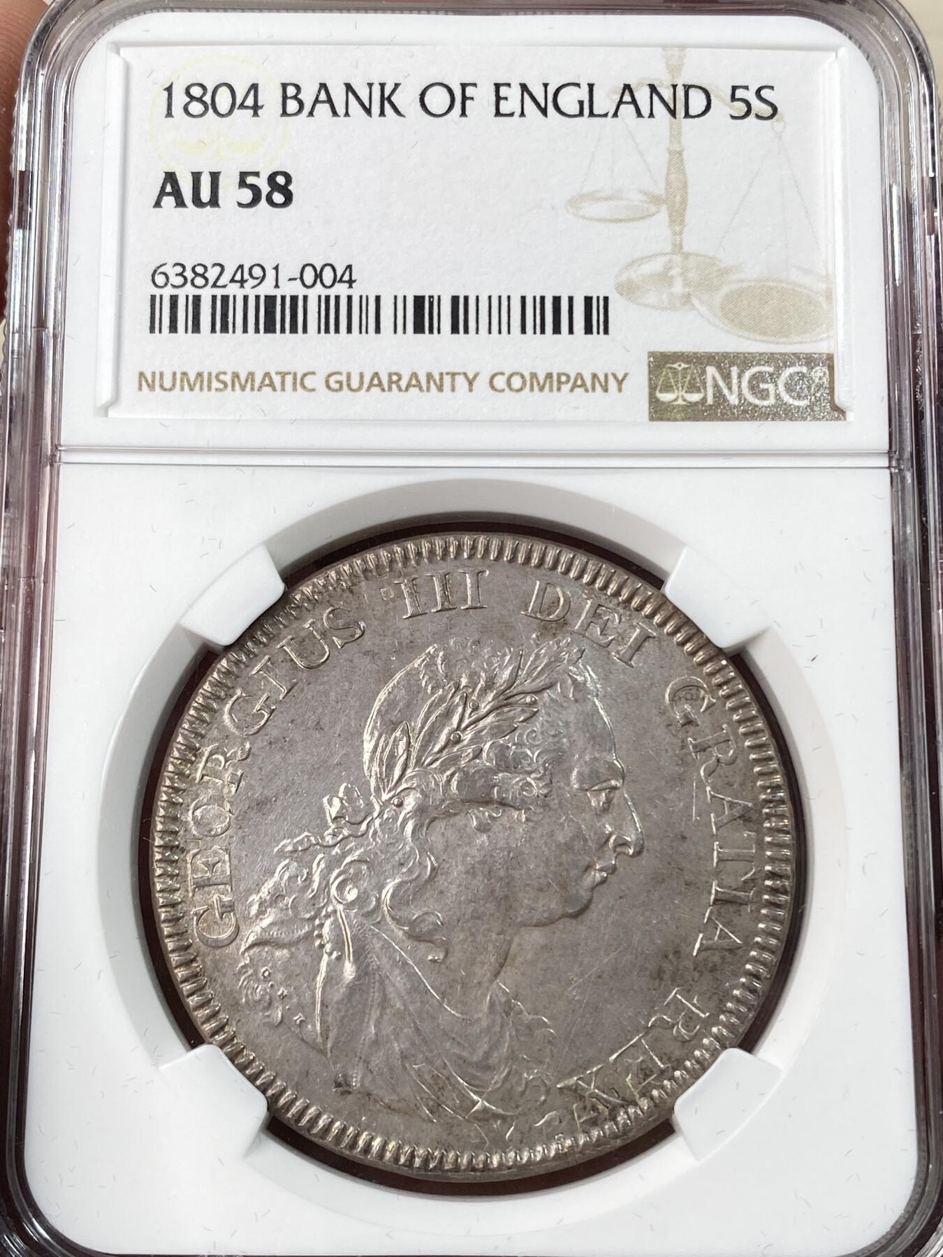 万国钱币拍卖第056期 NGC AU58 1804年英国乔治三世英格兰银行5先令大银币 英国白银短缺时期的产物 直接压印在西班牙双柱之上 双柱影子依稀可见 原味纸袋包浆非常诱人