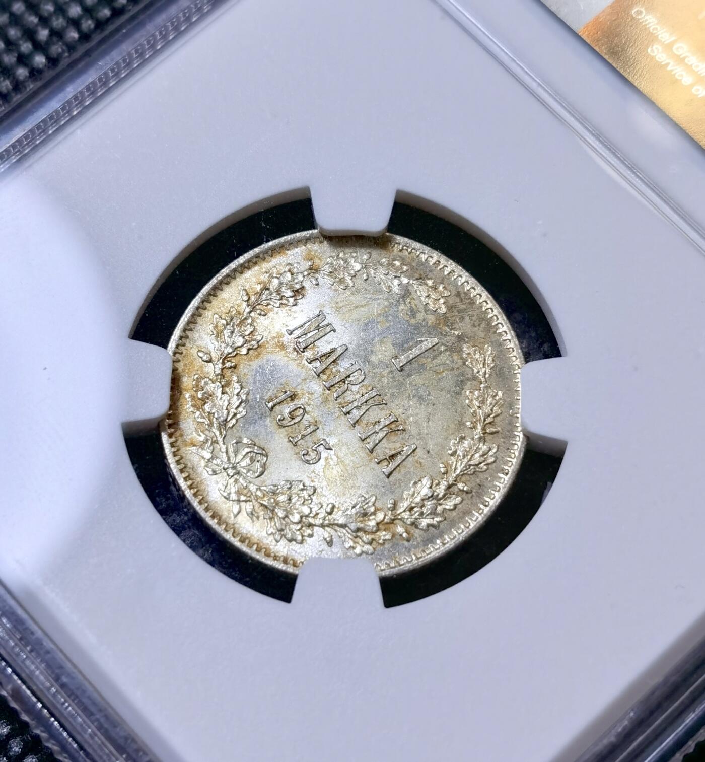 甄臻铺-世界币章拍卖（第40期）送拍享返佣金等优惠多多 NGC-UNC 1915年俄占芬兰1马克银币，因为表面粘了别的锈迹，给了stained，底板非常好，转光强烈，清理可达ms64左右的分数