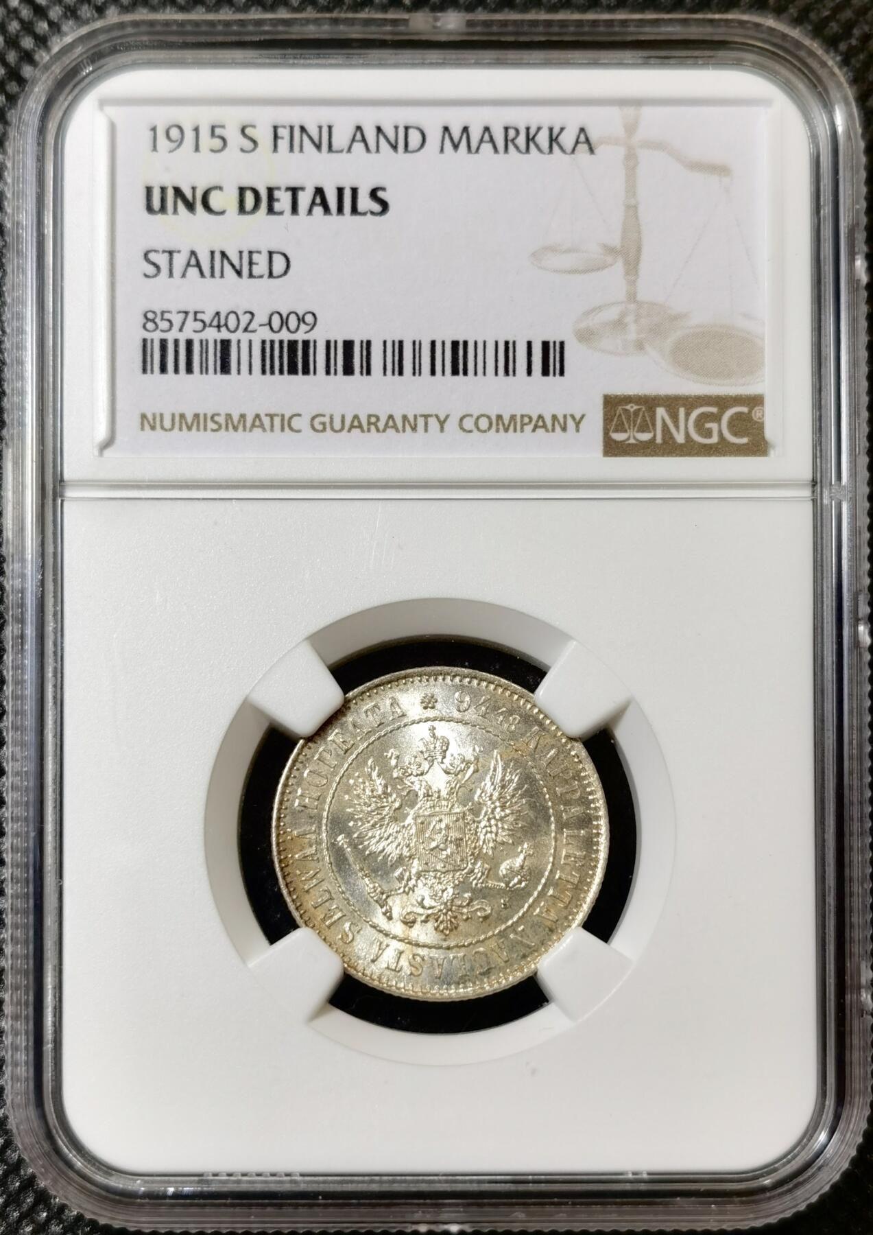 甄臻铺-世界币章拍卖（第40期）送拍享返佣金等优惠多多 NGC-UNC 1915年俄占芬兰1马克银币，因为表面粘了别的锈迹，给了stained，底板非常好，转光强烈，清理可达ms64左右的分数