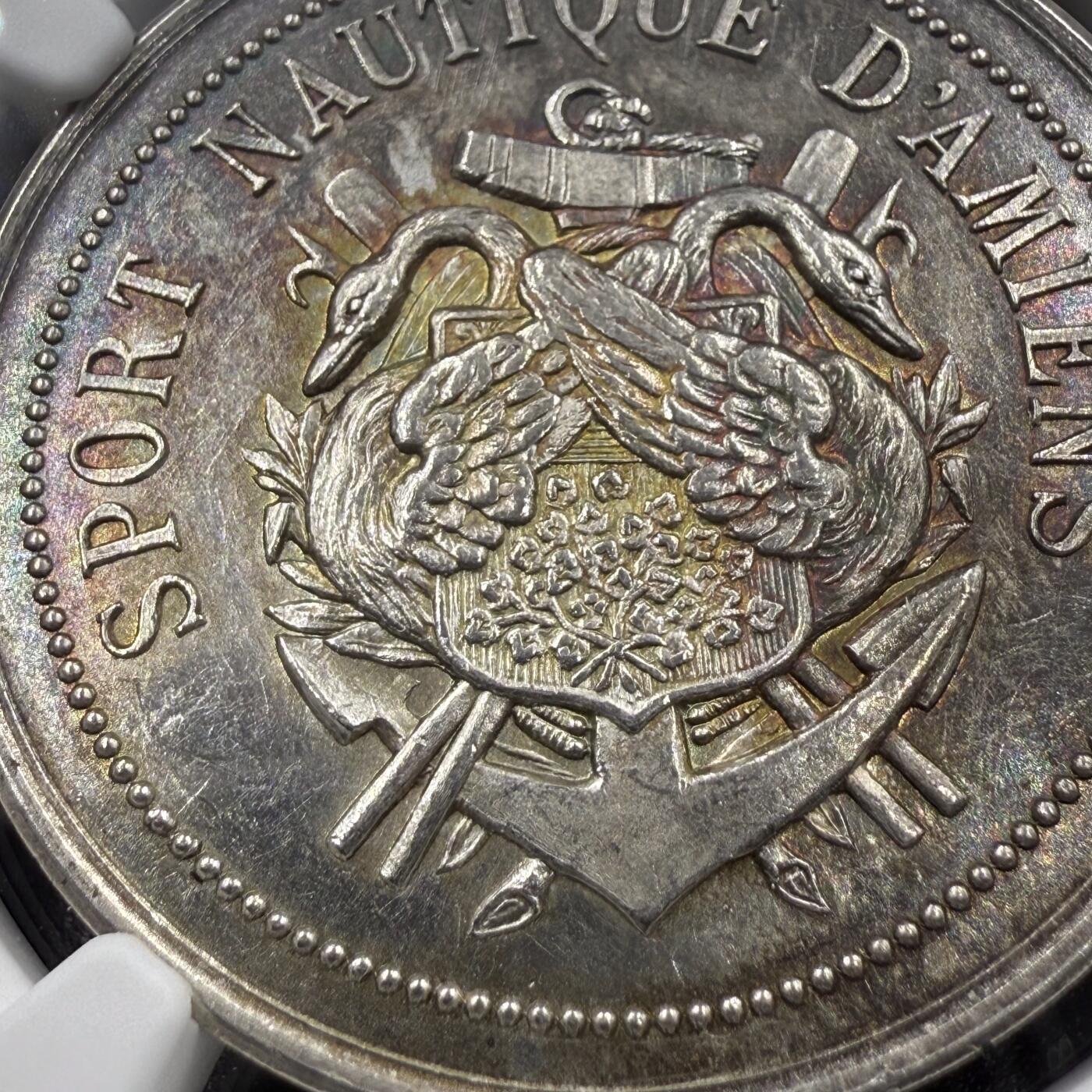 「木头集藏」章牌精品专场！ 1866法国昂热水上运动协会银章，MS 61，直径：34 mm，正面刻画天鹅、船锚及船桨等元素，寓意水上运动的优雅、灵动，少见银章，彩色氧化很美。