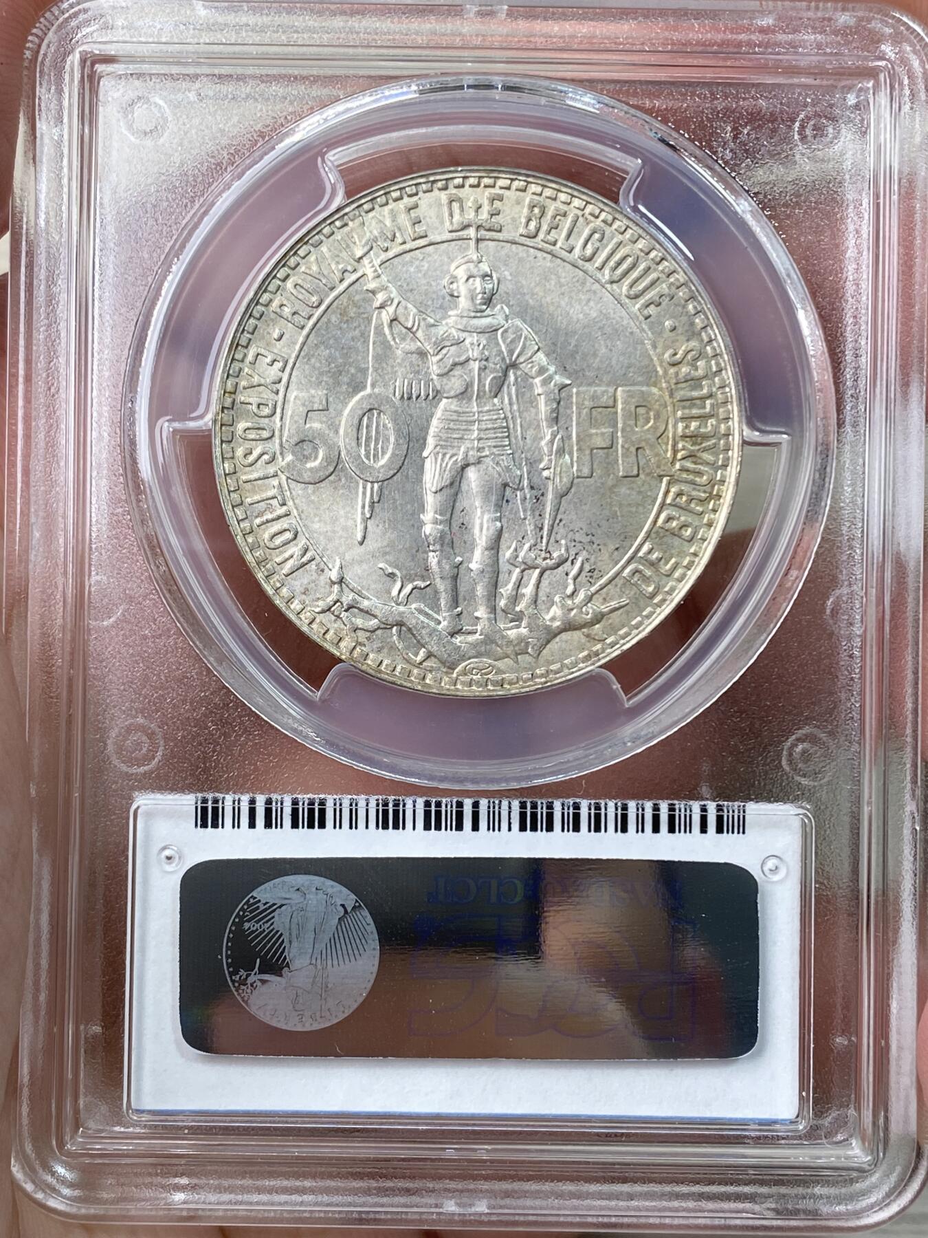 万国钱币拍卖第056期 PCGS MS66 1935年比利时50法郎纪念银币 布鲁塞尔国际博览会和比利时铁路百年 高分顶级品相 From the Roark Collection 原银强车轮霜光，黄油淡彩包浆，实物非常漂亮。正面:前卫设计的圣乔治屠龙，法语版铭文。背面:布鲁塞尔世博会大楼景观。边铭:SOUS LE REGNE DU ROI LEOPOLD III，在利奥波德三世国王的统治下。比利时皇家铸币厂。
