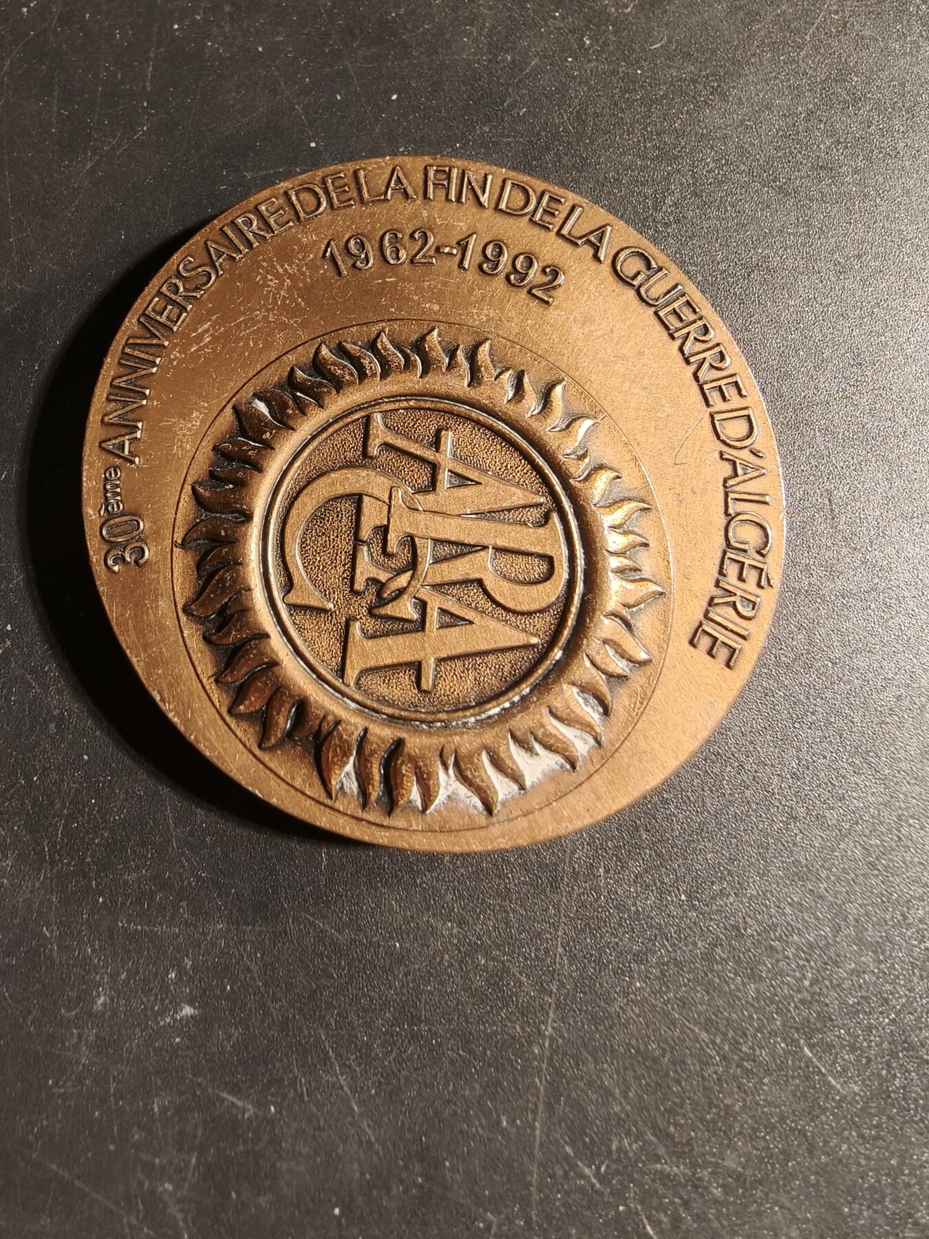 老王徽章第167期 法国退伍军人、战争受害者和战争之友协会阿尔及利亚战争30周年大铜章       高浮雕      正面描绘了和平鸽飞越被战争摧毁的城镇上空，背景是废墟和一片墓地，象征着对战争的控诉和对和平的渴望      直径 54mm.     重量104.1g