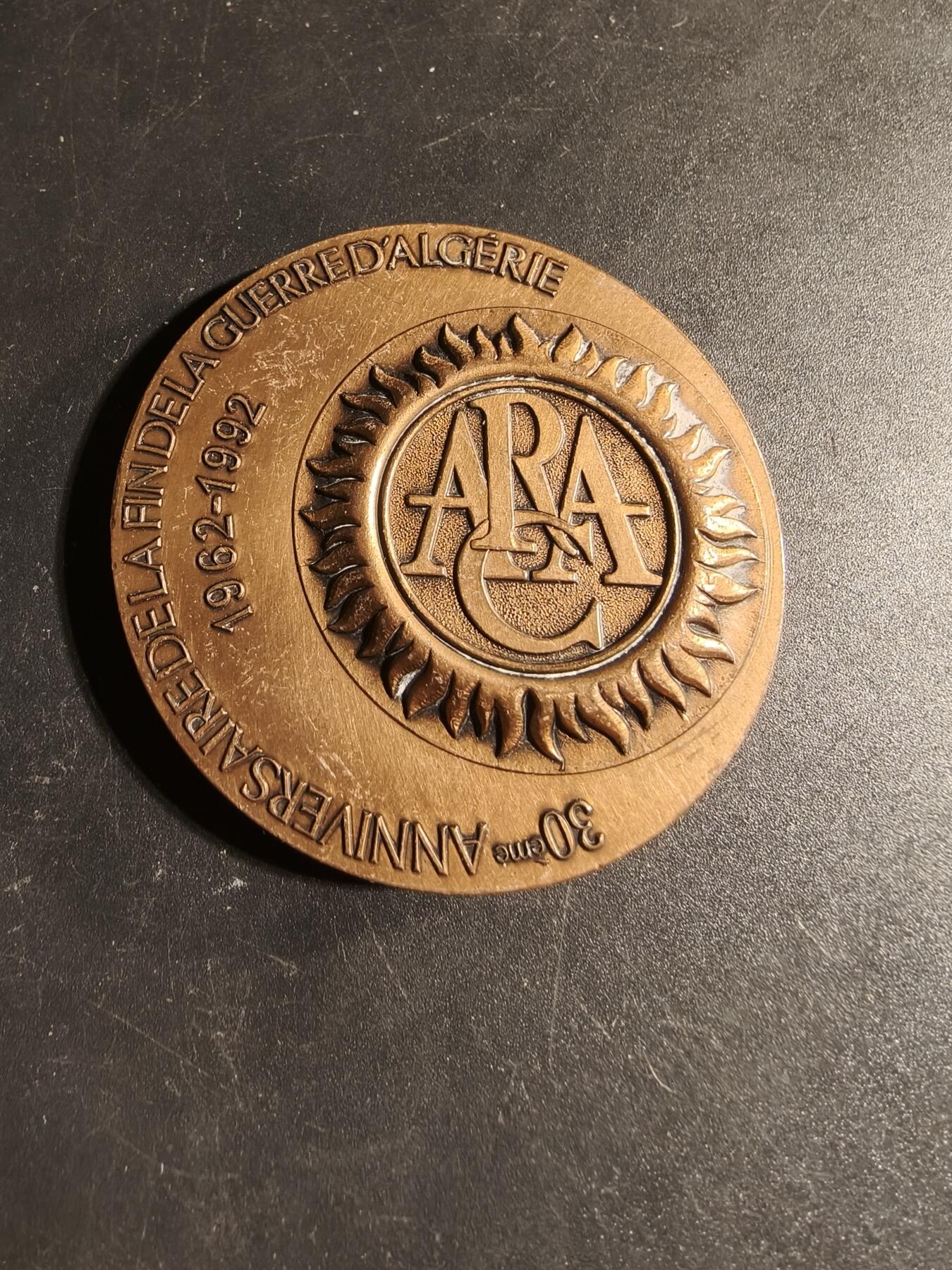 老王徽章第167期 法国退伍军人、战争受害者和战争之友协会阿尔及利亚战争30周年大铜章       高浮雕      正面描绘了和平鸽飞越被战争摧毁的城镇上空，背景是废墟和一片墓地，象征着对战争的控诉和对和平的渴望      直径 54mm.     重量104.1g
