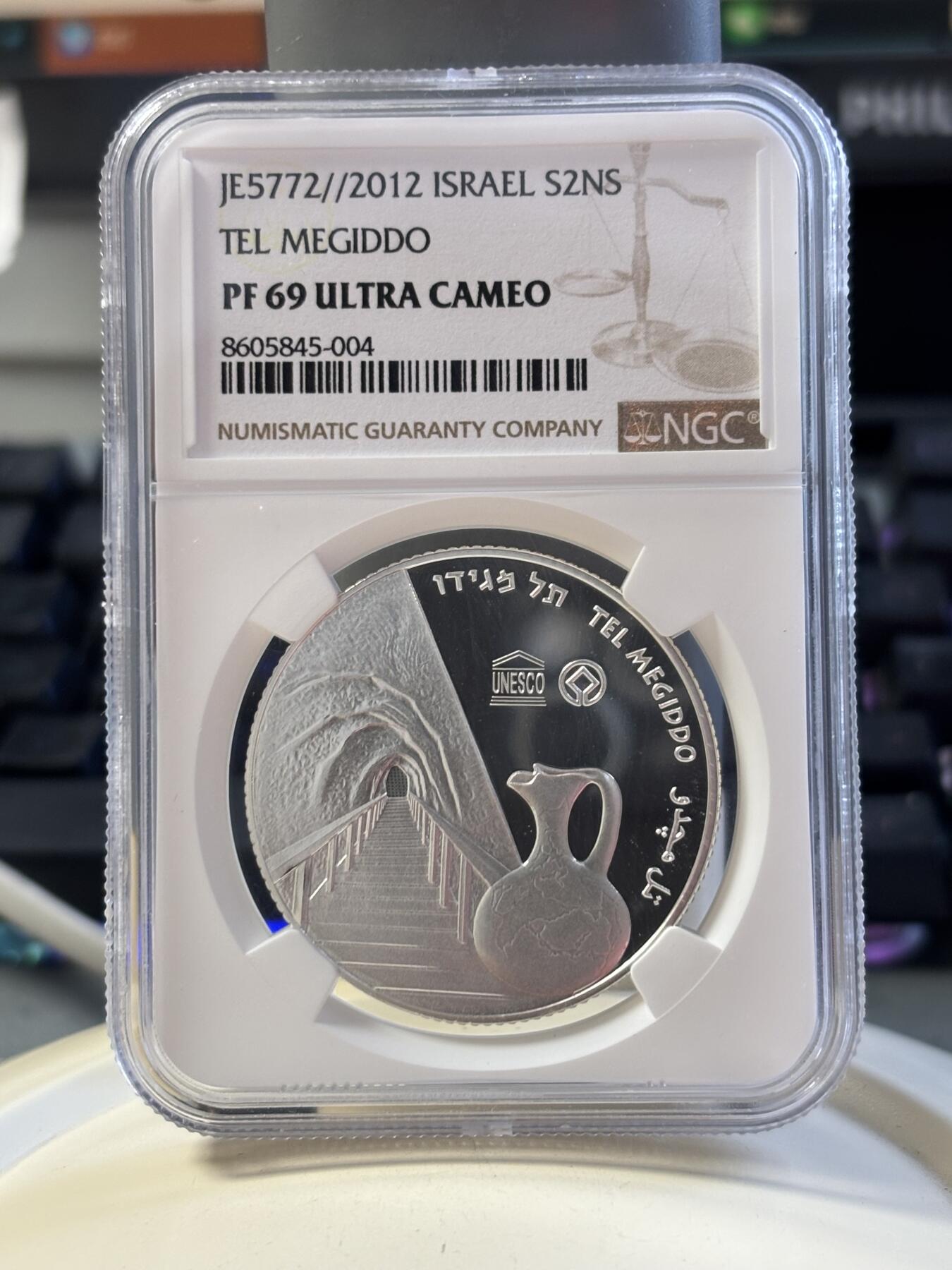 第183期拍卖 以色列2012年圣经系列美吉多山2新谢克尔PROOF银币NGC PF69UC，发行量3000枚，999银。美吉多山是《圣经·启示录》中世界末日善与恶最终决战之地，正面设计陶壶和山谷，通过透视图技法，尤其是山谷及通向内部的栈道，给人一种向里走的感觉，在二维平面银币表现出三维立体効果。原盒证封齐全。