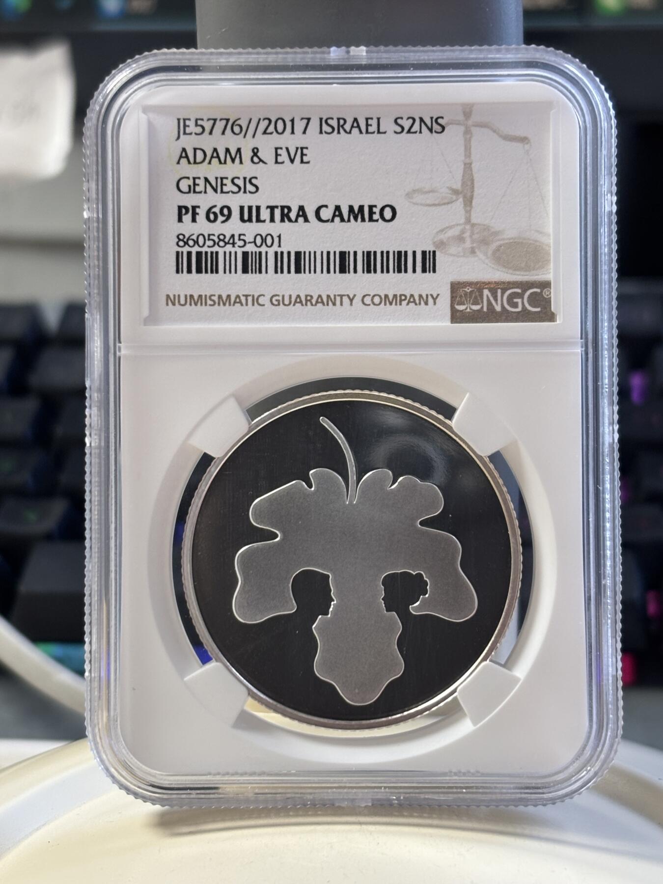 第183期拍卖 以色列2017年圣经系列亚当和夏娃2新谢克尔PROOF银币NGC PF69UC，发行量2800枚，999银。正面通过精制与磨砂工艺反差効果将亚当和夏娃在苹果叶中体现出爱的寓意。