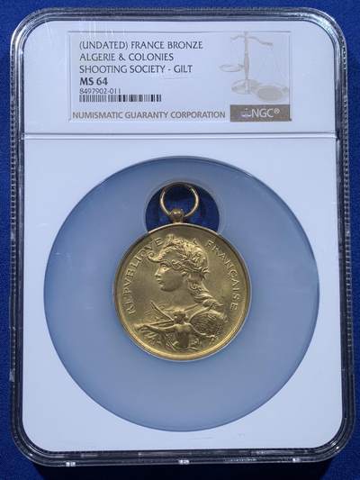 《竞宝斋》第444场 周日，周一，2场连拍 （全场包邮） - NGC MS64 约1890年代 法属阿尔及利亚殖民地 射击节镀金大铜章，欧洲射击节常见，殖民地射击节非常稀少。经典的玛丽安娜女神+女性天使，华丽优雅。金水很足，镀层极好。加大加厚盒装，收藏级品质