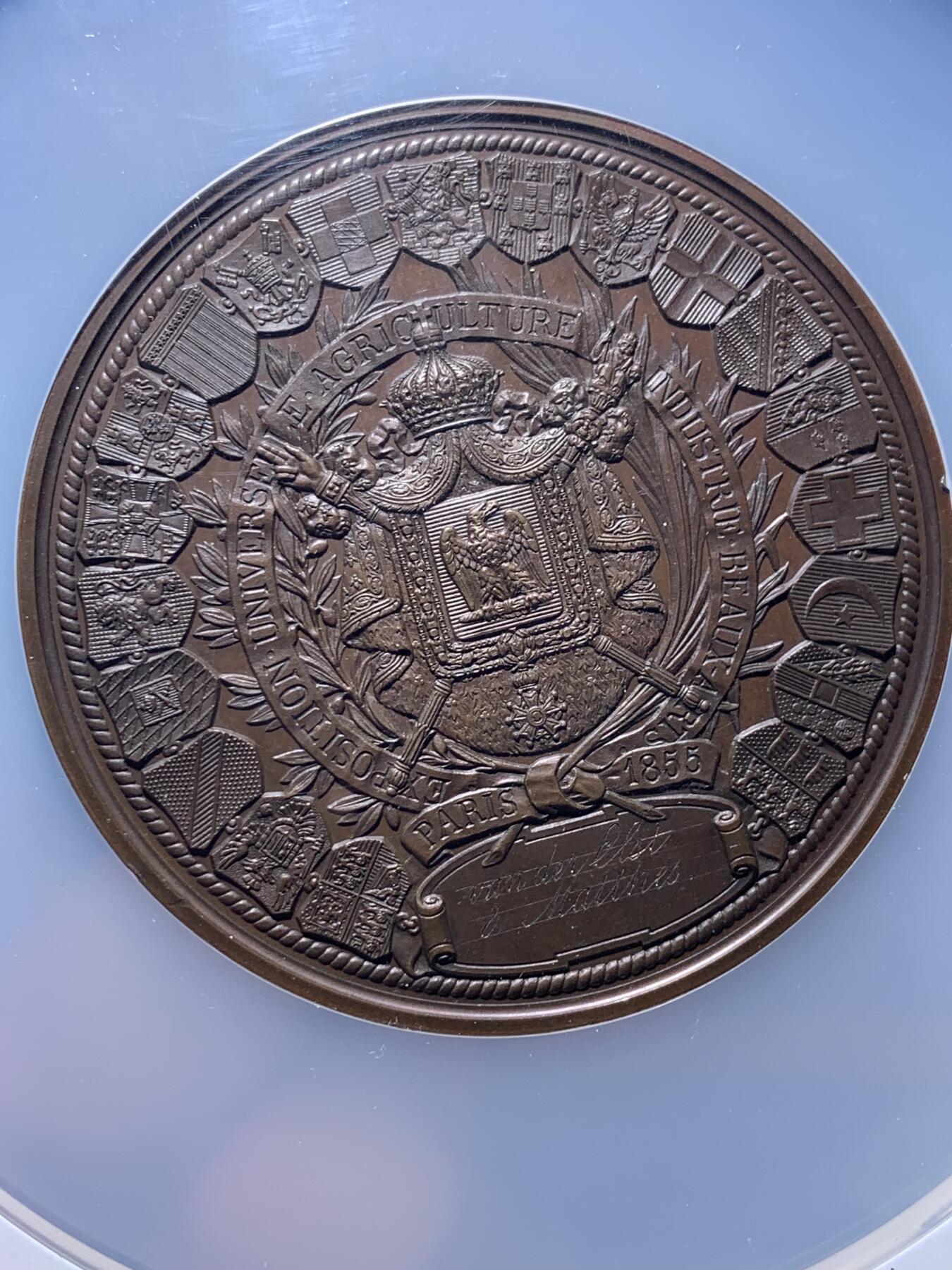 《竞宝斋》第444场 周日，周一，2场连拍 （全场包邮） NGC MS64BN 法国1855年巴黎世博会纪念大铜章，60mm，顶级高分。拿三章牌中的热门品种，20国徽章环绕波拿巴家族鹰徽，众星捧月，繁复华丽，记录拿破仑三世的巅峰时刻。手指边铭原铸品，加大加厚盒装