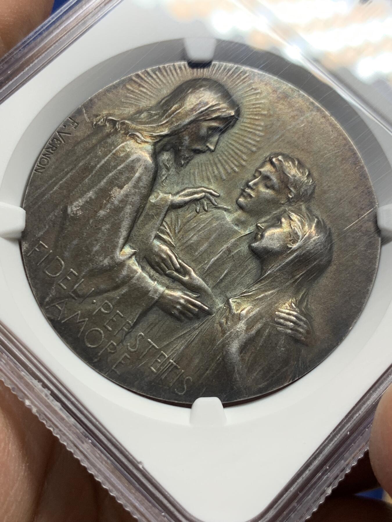 《竞宝斋》第444场 周日，周一，2场连拍 （全场包邮） NGC MS62 法国新艺术宗教婚礼稀有大银章，著名新艺术雕刻家：弗雷德里克-夏尔.维克托.德.韦尔农，以细腻的宗教题材浮雕著称。该章为更为稀少的背面无刻字版，适合新婚、结婚纪念刻字。正面场景：描绘yesu与使徒彼得、约翰（或抹大拉的马利亚）的互动FIDELI PERSTETIS AMORE拉丁语，意为**“你们对那忠信的恒守爱心”，背面：花卉：左下角的玫瑰（象征玛利亚的纯洁）与下方的百合（象征圣