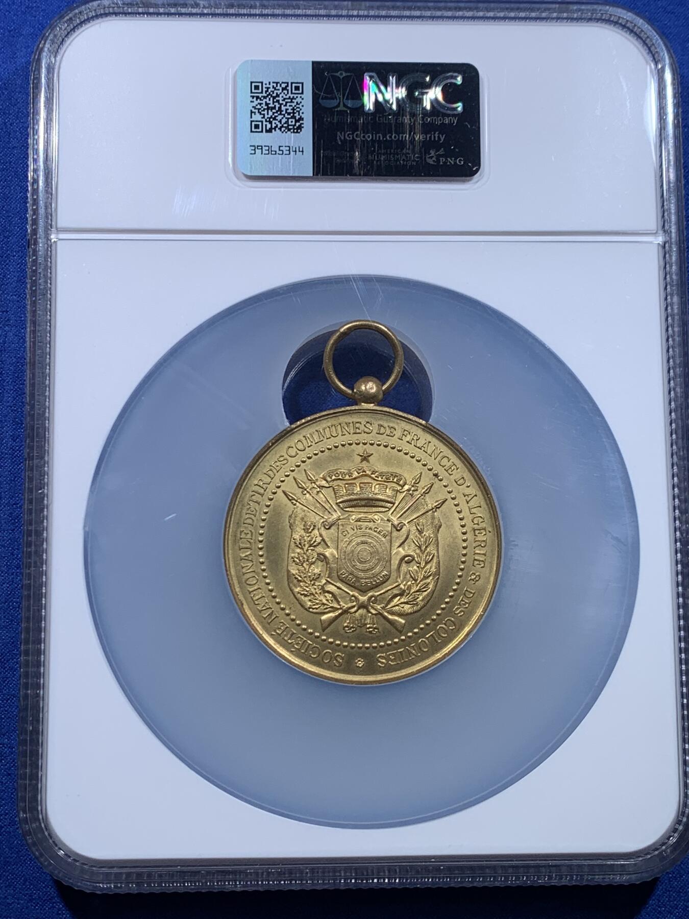 《竞宝斋》第444场 周日，周一，2场连拍 （全场包邮） NGC MS64 约1890年代 法属阿尔及利亚殖民地 射击节镀金大铜章，欧洲射击节常见，殖民地射击节非常稀少。经典的玛丽安娜女神+女性天使，华丽优雅。金水很足，镀层极好。加大加厚盒装，收藏级品质