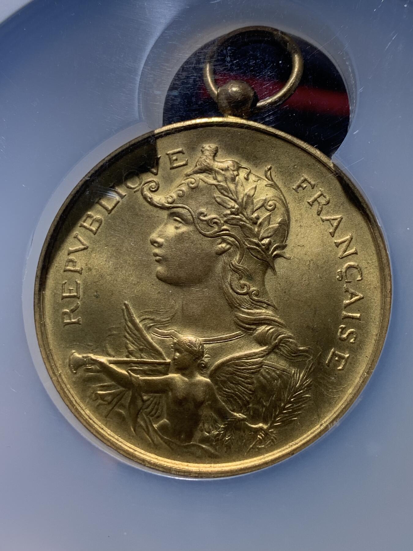 《竞宝斋》第444场 周日，周一，2场连拍 （全场包邮） NGC MS64 约1890年代 法属阿尔及利亚殖民地 射击节镀金大铜章，欧洲射击节常见，殖民地射击节非常稀少。经典的玛丽安娜女神+女性天使，华丽优雅。金水很足，镀层极好。加大加厚盒装，收藏级品质