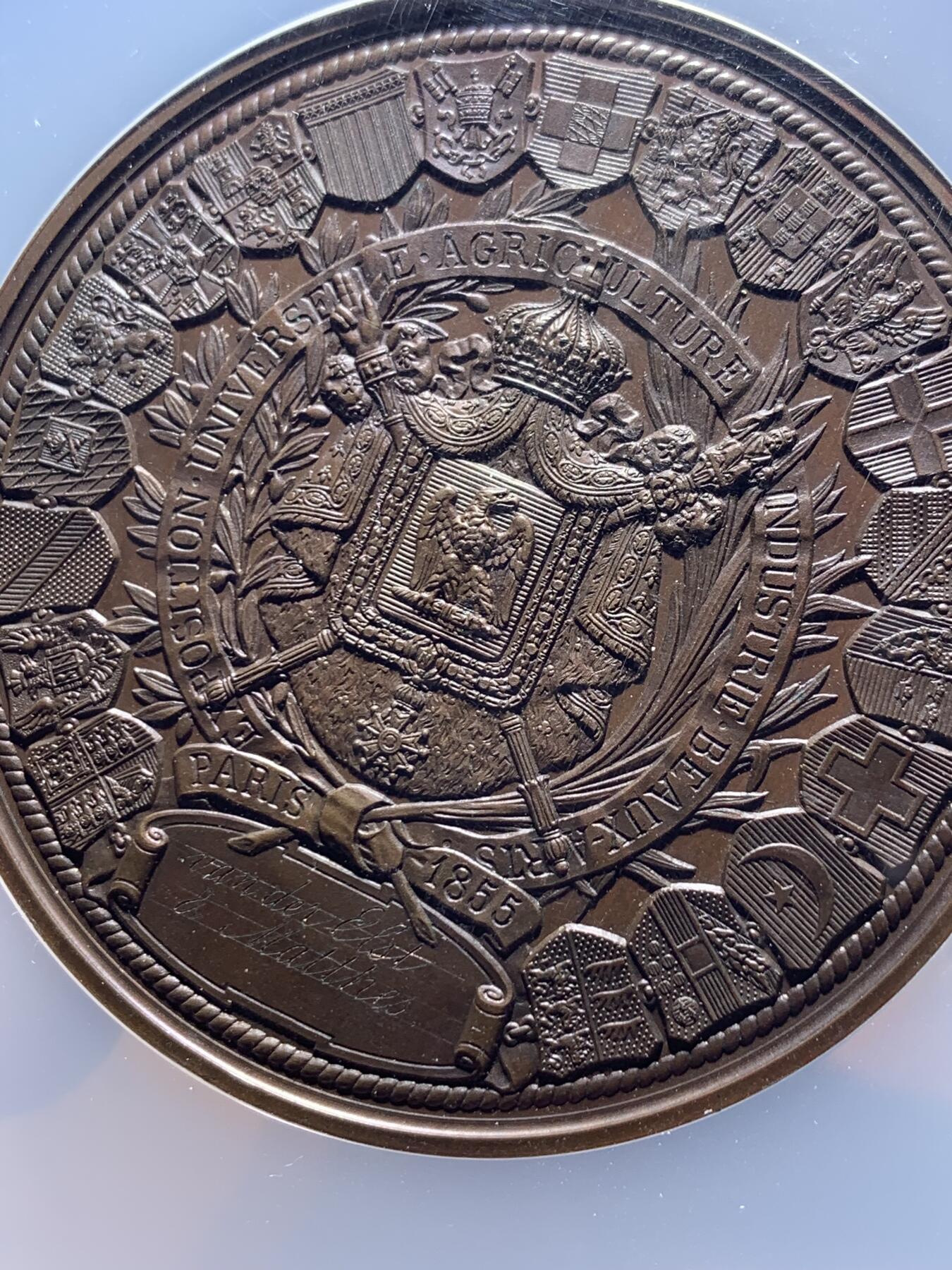 《竞宝斋》第444场 周日，周一，2场连拍 （全场包邮） NGC MS64BN 法国1855年巴黎世博会纪念大铜章，60mm，顶级高分。拿三章牌中的热门品种，20国徽章环绕波拿巴家族鹰徽，众星捧月，繁复华丽，记录拿破仑三世的巅峰时刻。手指边铭原铸品，加大加厚盒装