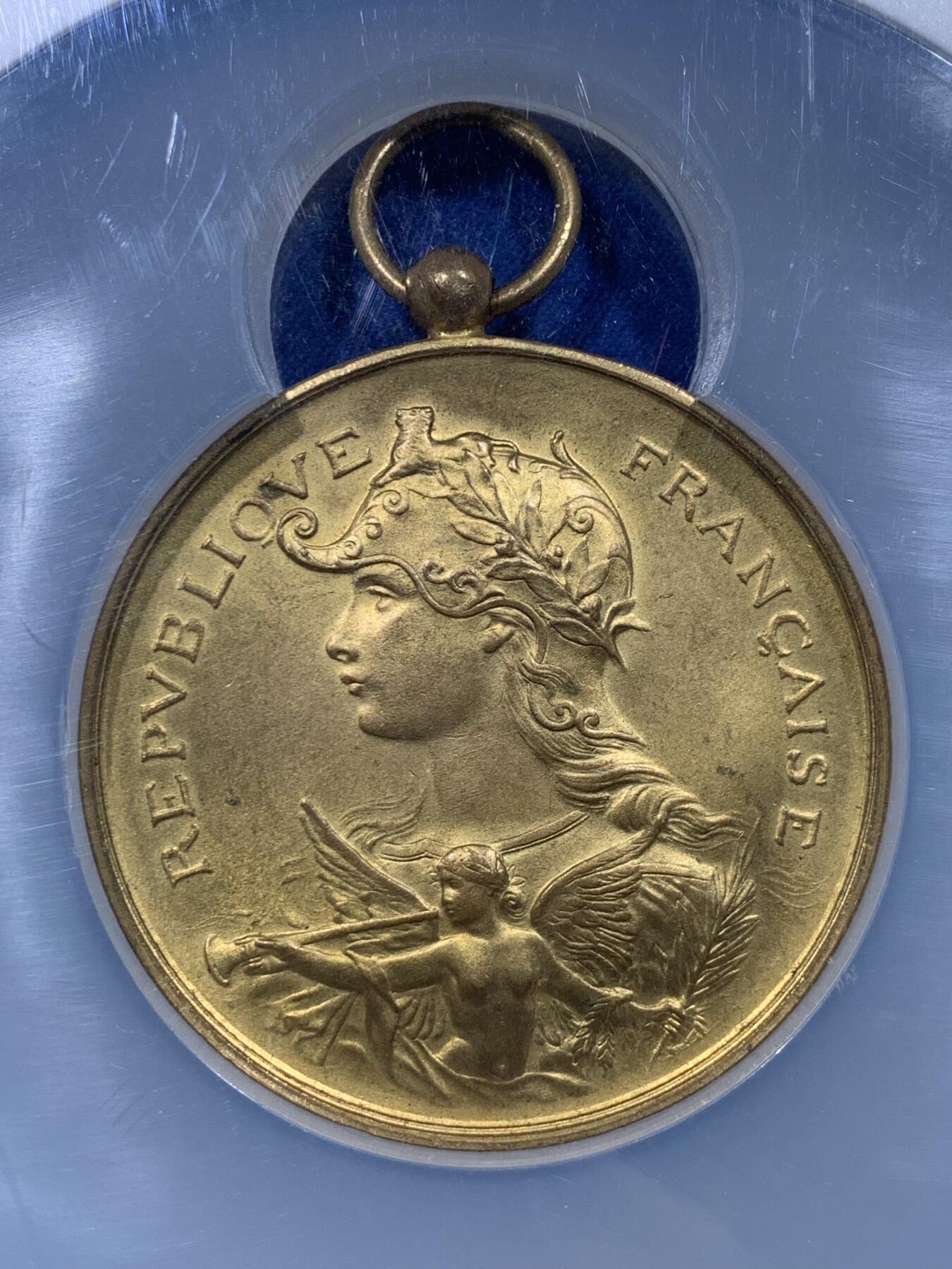 《竞宝斋》第444场 周日，周一，2场连拍 （全场包邮） NGC MS64 约1890年代 法属阿尔及利亚殖民地 射击节镀金大铜章，欧洲射击节常见，殖民地射击节非常稀少。经典的玛丽安娜女神+女性天使，华丽优雅。金水很足，镀层极好。加大加厚盒装，收藏级品质