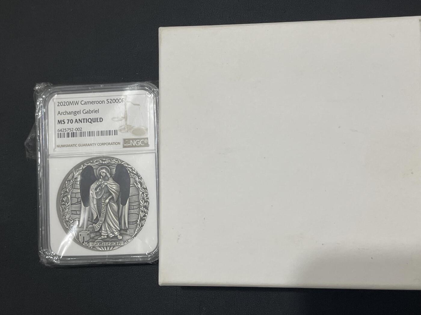 ❤️【币观天下】❤️ 第333期钱币拍卖- 2025.12.5周五晚上6点半场-长期征集拍品 喀麦隆天使系列首枚天使加百列镶嵌玻璃2盎司仿古银币，盒证齐全，ngc70