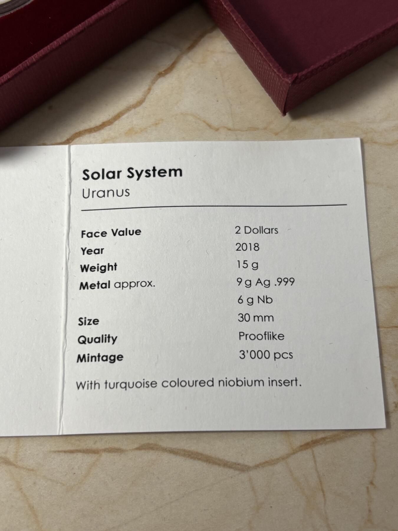 第184期拍卖 帕劳2018年太阳系系列2天王星镶蓝色铌金属彩银币，金属:999银/998铌，重量:15克(8.3克银/6.7克铌），发行：3000枚