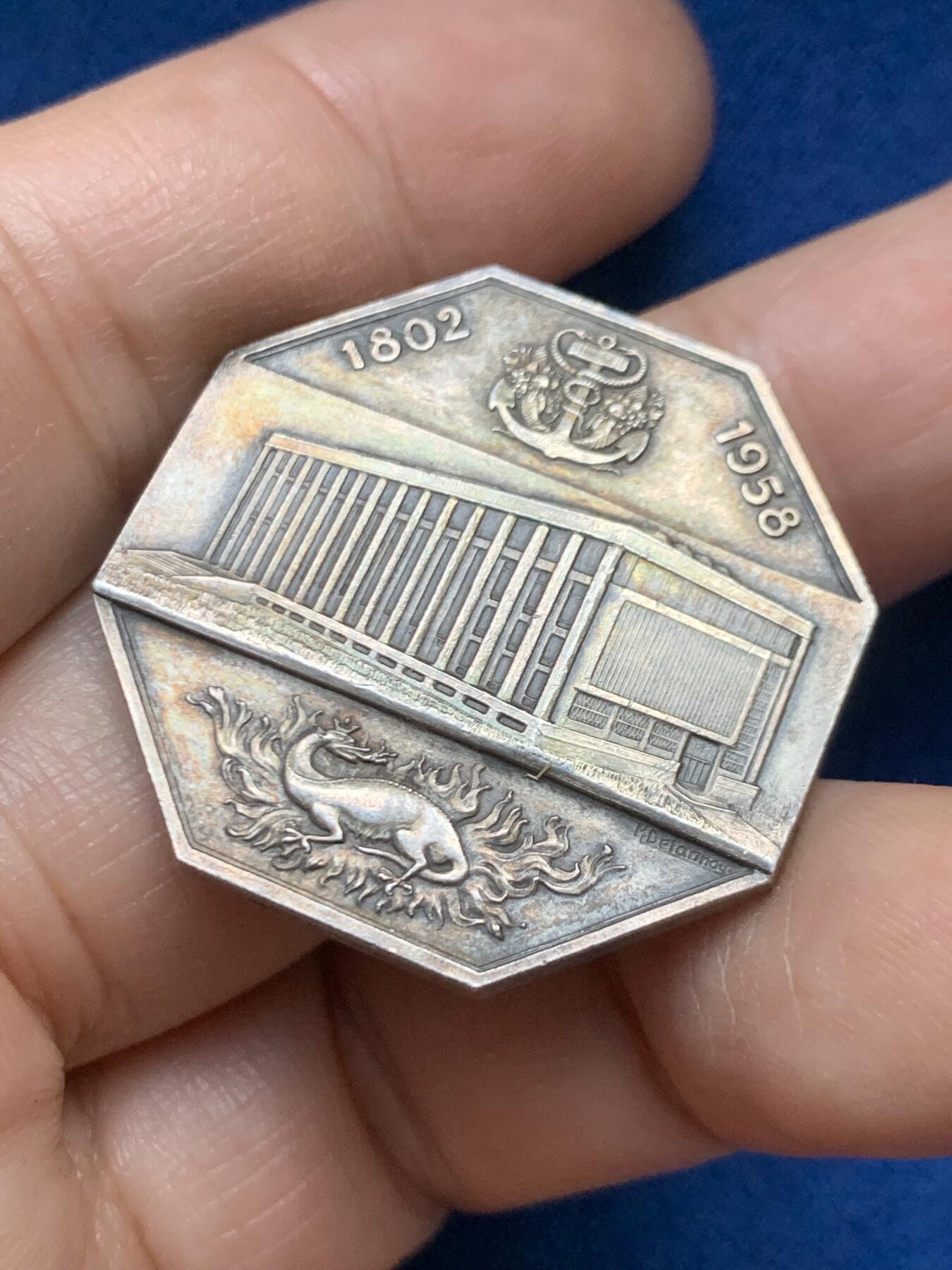 《竞宝斋》第446场 周日，周一，2场连拍 （全场包邮） 法国1958年勒阿弗尔商会八角银质代币 19.3克 32mm 丰饶角1银标  正面：十八世纪勒阿弗尔港全景，停泊着多艘帆船； 背面：锚形图案标注年份「1802-1958」，火焰中小火龙图案，中央为商会大楼景观；下方设计师签名「M·德尔努瓦」