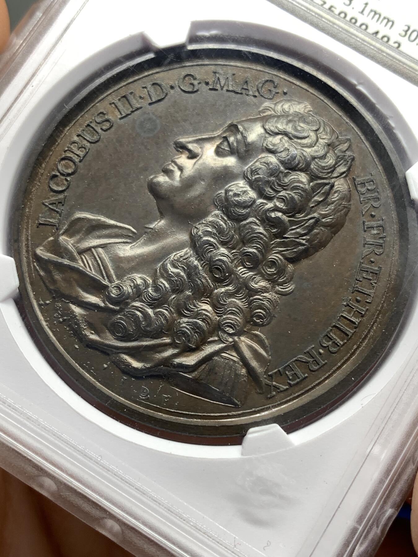 《竞宝斋》第446场 周日，周一，2场连拍 （全场包邮） 华夏 MS62 英王詹姆斯二世纪念铜章，英国历代君主纪念铜章系列之斯图亚特王朝末代国王詹姆斯二世，目录编号：Eimer 384。著名雕模大师瑞士人Dassier的作品，此版属于在整个英王系列里很受欢迎的热门国王品种。开放式盒评级，高浮雕艺术性很强，全面氧化形成“巧克力”色包浆，底板细腻光洁，呈现类精制工艺状态！