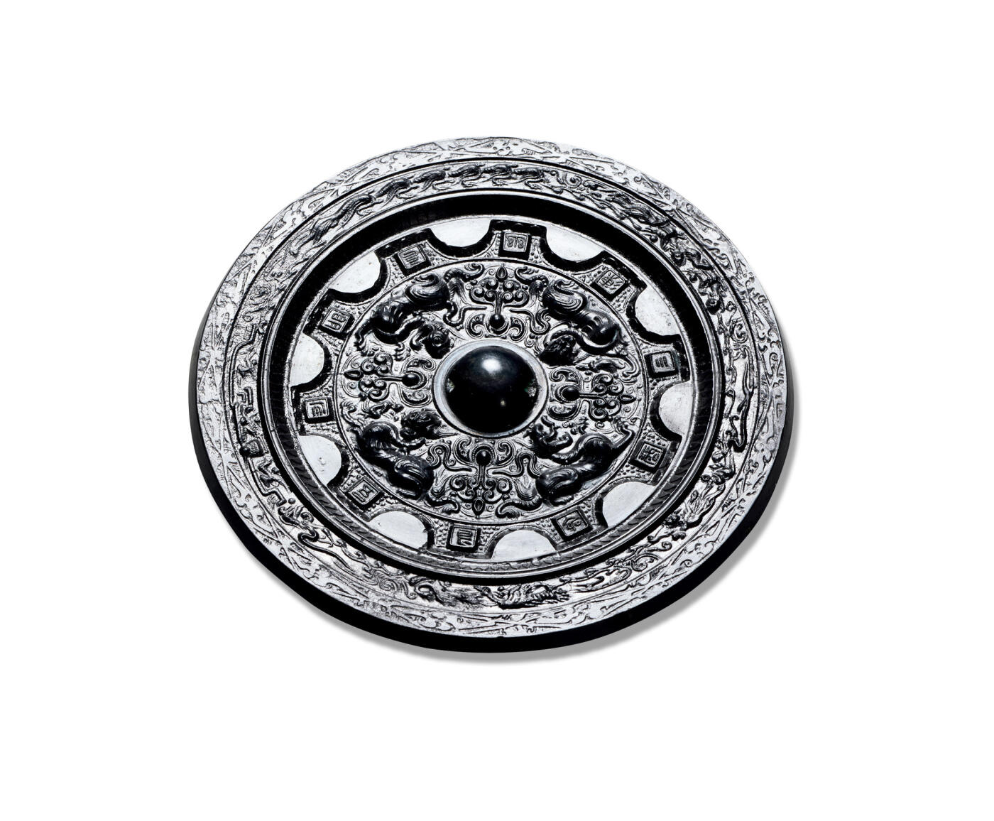 上海匡时2025年秋季拍卖会 中国历代钱币 铜镜专场 半圆方枚四兽花卉镜 圆形，圆钮，圆钮座。铜镜内圈浮雕一周神人瑞兽图案，其中四只大瑞兽深邃犀利，神态生动，羽人及花卉纹饰间隔其中，外圈饰十二枚相间的方枚与半圆，方枚上刻铭文：「吾作明竟，幽湅三商，命长」，铭文字体虽小但是清晰可辨。镜缘起台，内饰一周羽人驾舟车乘飞龙出行图，外饰一周瑞兽纹。此镜纹饰细腻，题材稀少，版工一流。