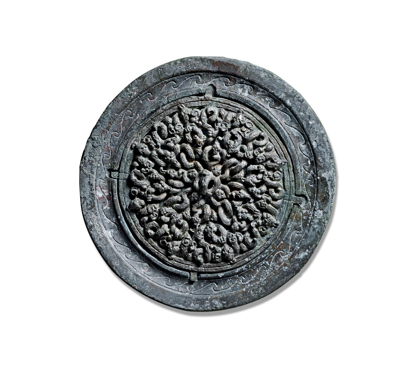 上海匡时2025年秋季拍卖会 中国历代钱币 铜镜专场 镂空二十四龙复合镜 圆形，弓形钮，镂空圆钮座。镜背与镜体以镶嵌复合工艺制成，镜缘处设有四个固定齿槽，呈十字形排列。主纹饰为二十四条相互缠绕的蟠螭纹绕钮分为四区，构成镂空图案。其中最内区四龙头部与钮座相接，第二区四龙龙头朝向镜缘与钮区四龙呈十字分布，龙身作正S形弯曲，龙尾延伸向镜钮；第三区八龙头朝外伸向镜钮，身躯呈反S形盘绕。最外区八龙咬向镜缘。二十四龙屈曲盘绕，昂首张目，眉眼清晰，龙鳞细密，刻画入