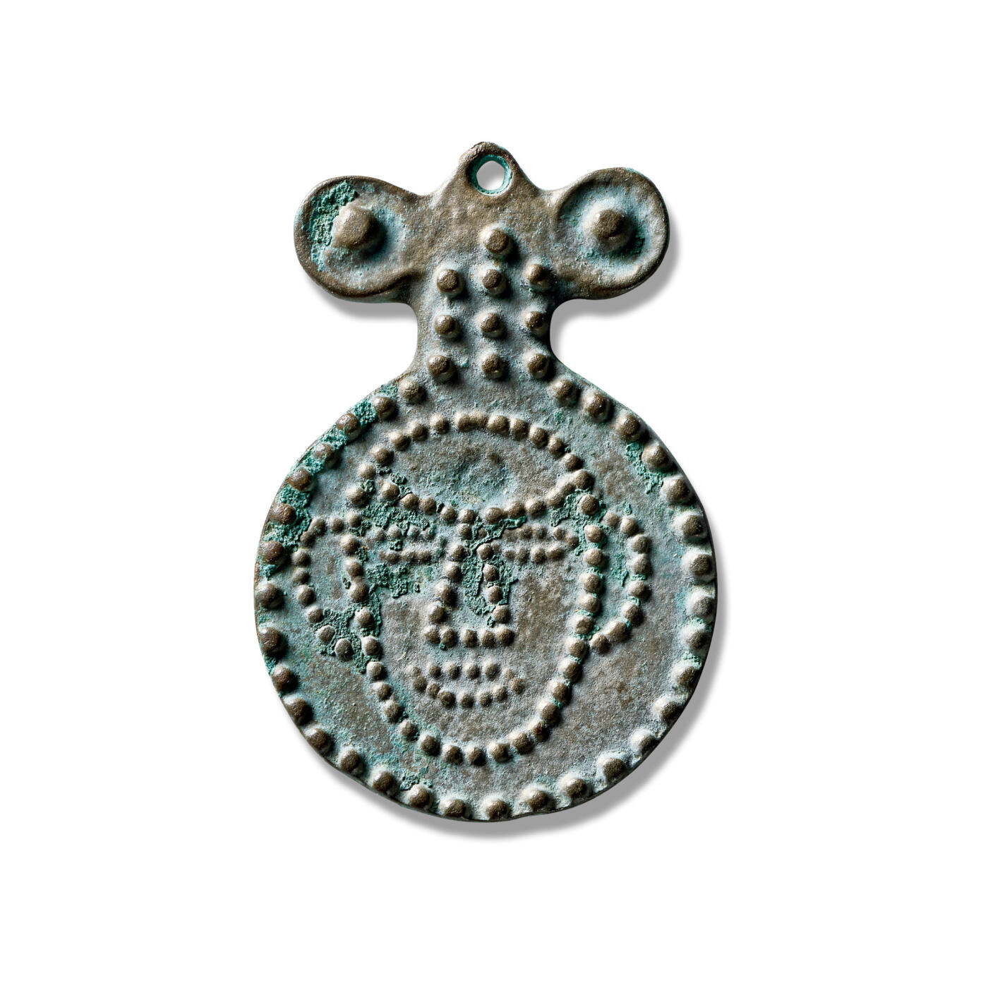 上海匡时2025年秋季拍卖会 中国历代钱币 铜镜专场 神人面牌饰护心挂镜 此件挂饰整体呈牌状，外区以密集的大乳钉环绕一周，并填满边框。内区则以细密的小乳钉勾勒出神人面部图案。纹饰主题鲜明，反映了古代游牧民族对神祇的崇拜与敬意，推测为佩挂于胸前以求庇护之用。此镜品相完好，题材独特，存世稀少，保存状态上乘，实属收藏之佳品。