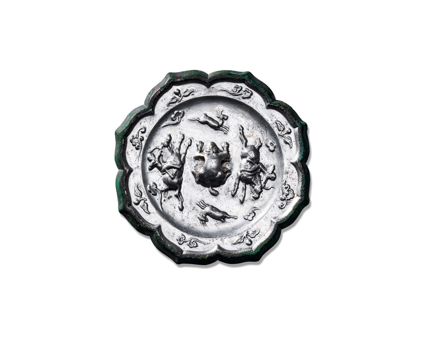 上海匡时2025年秋季拍卖会 中国历代钱币 铜镜专场 骑射狩猎纹镜 八出菱花形，俯兽钮。装饰纹样分为内外两区：内区为一周骑射狩猎图案，描绘两名猎人绕钮追逐走兽。两人骑马持弓，前方一鹿作惊惶逃窜状，将古人狩猎图景描绘得淋漓尽致。图案外环一周凸弦纹，外区每瓣葵瓣内饰以浮雕花蝶纹。纹饰精工细刻，布局缜密。