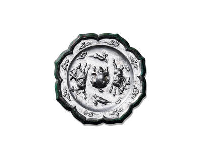 上海匡时2025年秋季拍卖会 中国历代钱币 铜镜专场 - 骑射狩猎纹镜 八出菱花形，俯兽钮。装饰纹样分为内外两区：内区为一周骑射狩猎图案，描绘两名猎人绕钮追逐走兽。两人骑马持弓，前方一鹿作惊惶逃窜状，将古人狩猎图景描绘得淋漓尽致。图案外环一周凸弦纹，外区每瓣葵瓣内饰以浮雕花蝶纹。纹饰精工细刻，布局缜密。