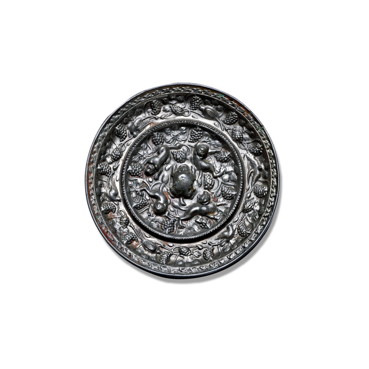 上海匡时2025年秋季拍卖会 中国历代钱币 铜镜专场 海兽葡萄镜 圆形，伏兽钮。一圈连珠纹凸梁将镜背纹饰分为内外两区。内区纹饰以高浮雕四只海兽为主，皆身躯曲卧，昂首仰天，攀援蹲伏于葡萄枝蔓之间。外区一圈饰以六只禽鸟，或展翅飞翔，或停栖于葡萄枝蔓间。镜缘高耸，缓倾面装饰连排卷云纹。闻德评级：82，带木盒。