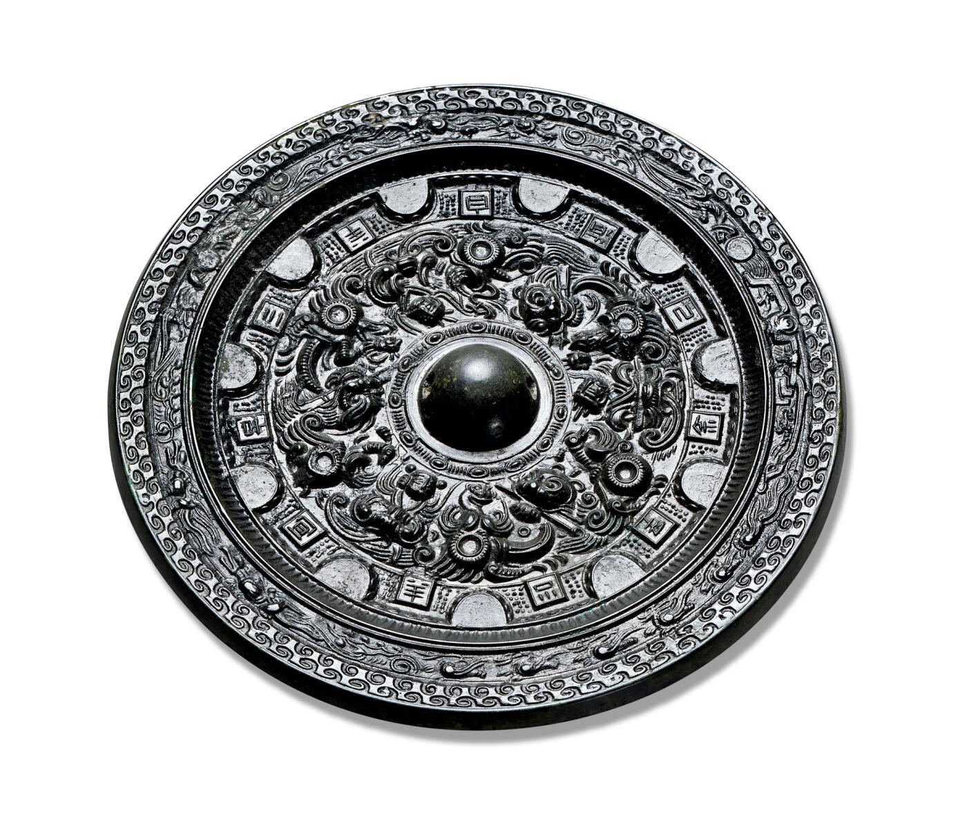 上海匡时2025年秋季拍卖会 中国历代钱币 铜镜专场 半圆方枚神人神兽镜 圆形，圆钮，圆钮座。主体纹饰采用高浮雕技法饰一周浮雕神人神兽图案，以四只神态各异的神兽为界，将纹饰分为四组，以钮为中心放射性布局。外区有凸起的半圆和方枚相排列，半圆侧面亦饰以极精致的半圆纹饰，与方枚之间的空白皆以点状细小乳钉填充，精美异常。每一方枚均有一字连读为：三羊自有己余去不羊宜古。方枚之外则是一圈细密的锯齿纹。镜缘处内圈饰一周神人驾龙车，乘鸾鸟，腾云驾雾出巡图。