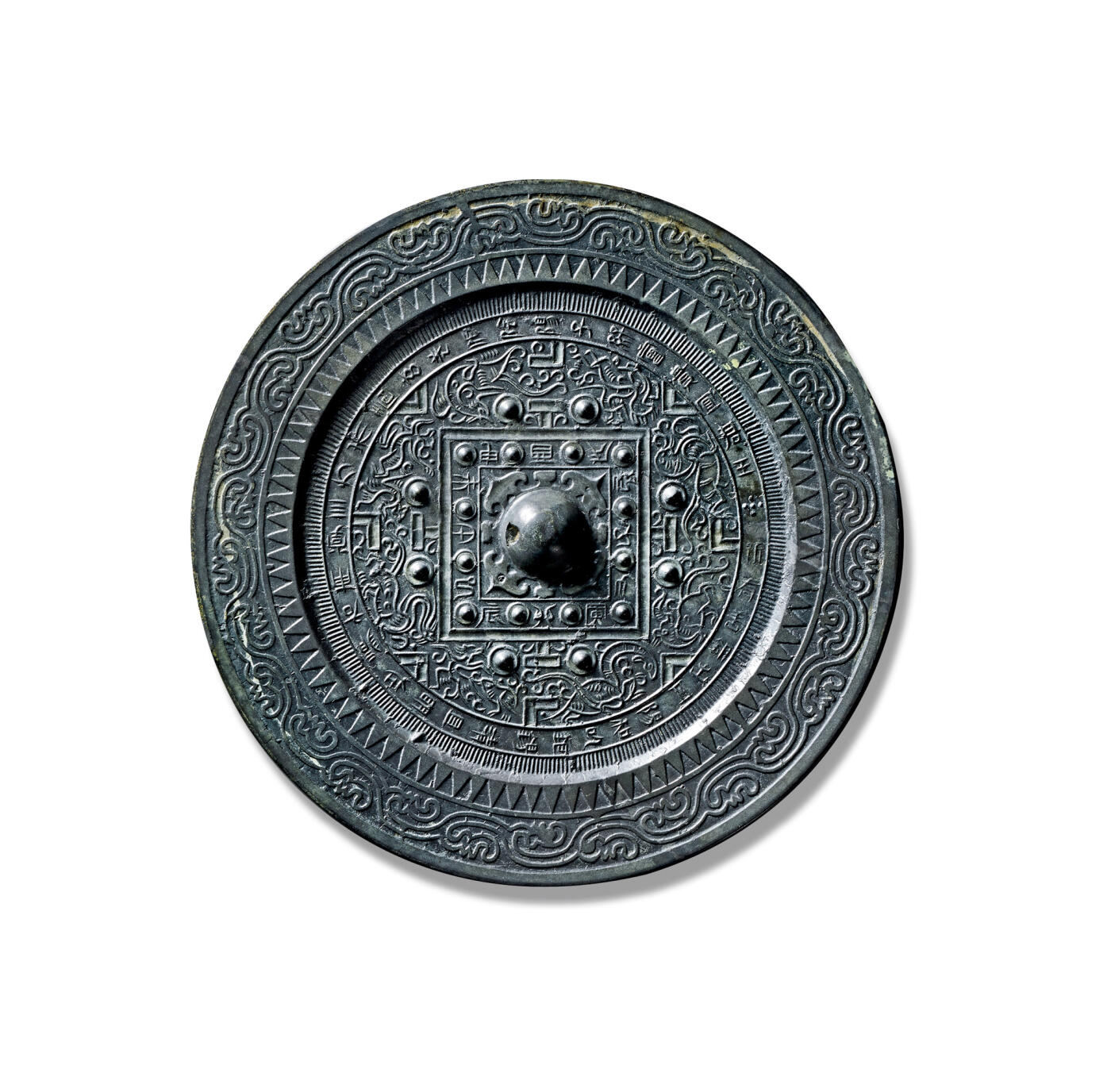 上海匡时2025年秋季拍卖会 中国历代钱币 铜镜专场 “新有善铜”四灵神兽规矩镜 圆形，圆钮，柿蒂纹钮座。钮外设双线凹面方格，内饰花苞纹，四边各置十二枚圆座乳钉，乳钉间分列篆书十二地支铭文。方格之外，以四组“T”纹两侧有圆钮座八乳钉，与博局纹共同将主纹饰划分为四方八区。各区纹饰以“V”纹为界，两两相对：青龙对羽人，白虎对独角山羊，朱雀对神鸟，玄武对瑞兽。纹饰间隙填以缭绕的云气纹，使画面更显灵动饱满。主纹饰外环绕一圈篆书铭文：“新有善铜出丹阳，和已银锡