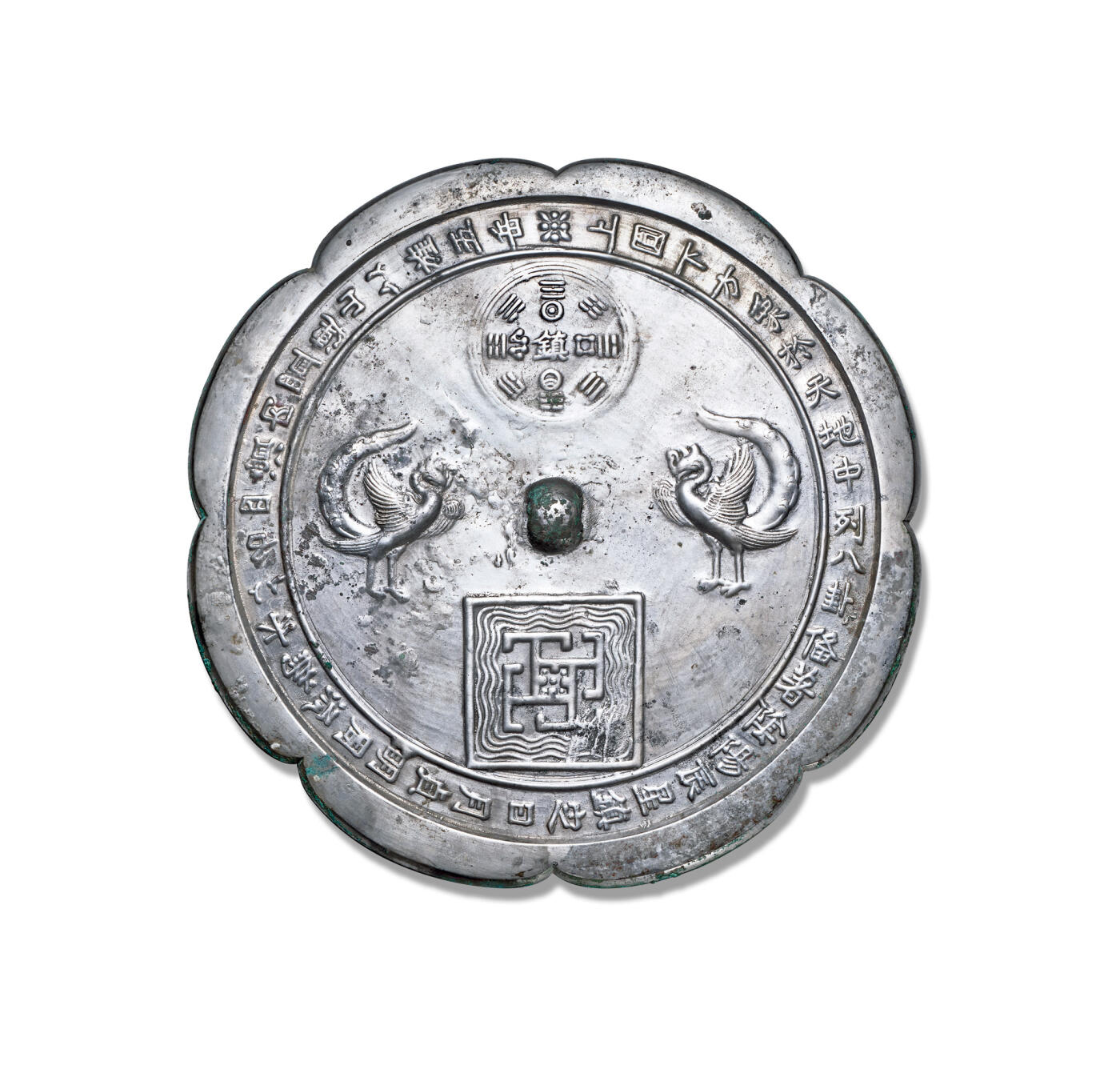 上海匡时2025年秋季拍卖会 中国历代钱币 铜镜专场 双鸾道教铭文镜 八出菱花形，圆钮，主题纹饰为两只对立的鸾鸟，鸾为凤凰之属，象征吉祥；上侧圆形八卦图案，中间“镇”字铭文，“镇”字上下日月纹，左右为星辰；下侧为方形图案，里边有水波纹和代表五岳的方块图案，上圆下方，意为天圆地方，五岳四渎。镜缘一周铭文：“上圆下方，象于天地，中列八卦，备着阴阳，辰星镇定，日月贞明，周流为水，以名四渎，内置连山，以旌五岳。”此铭文十分细致的解读了镜中纹饰，将道教文化展现